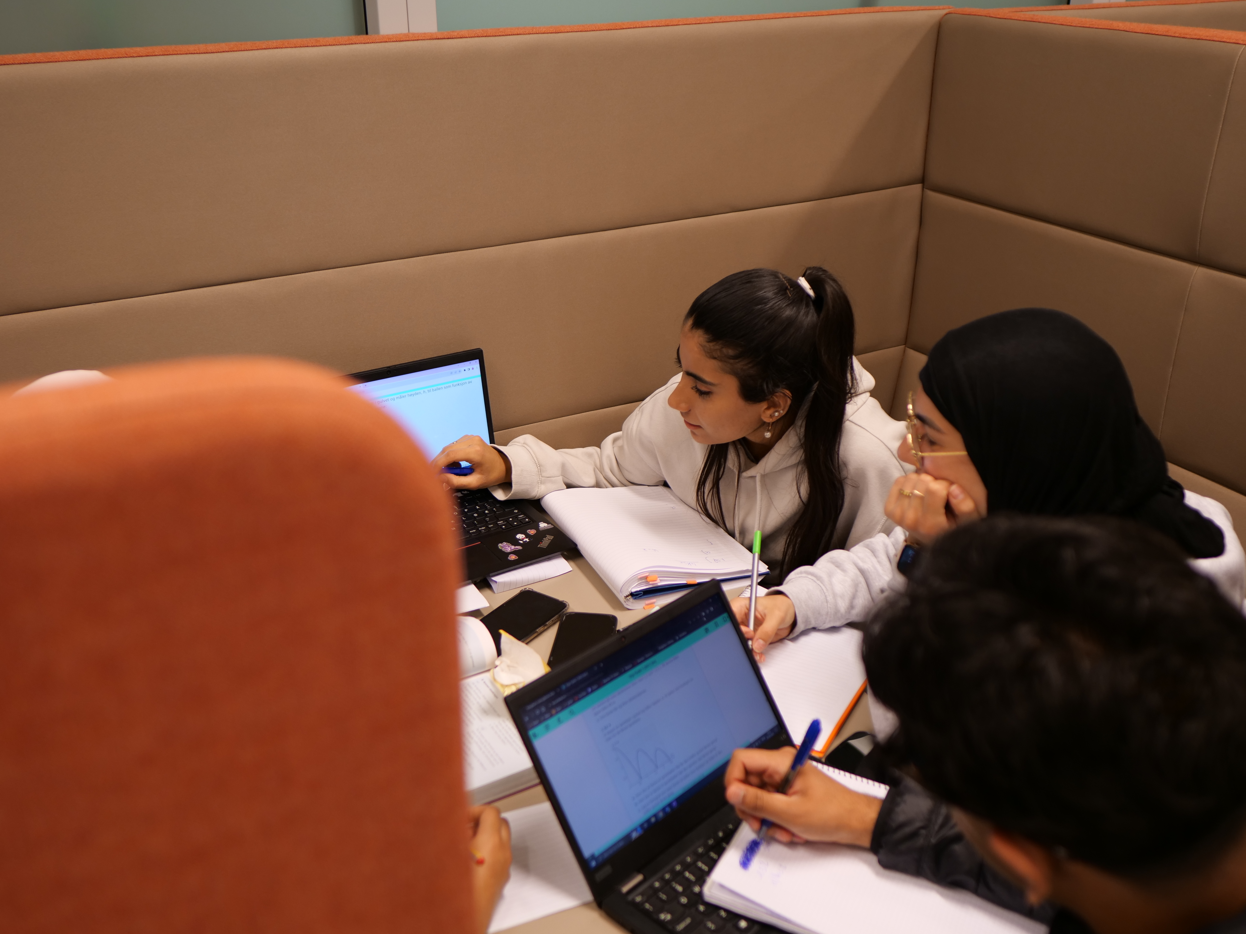 En gruppe mennesker som sitter ved et bord med bærbare datamaskiner