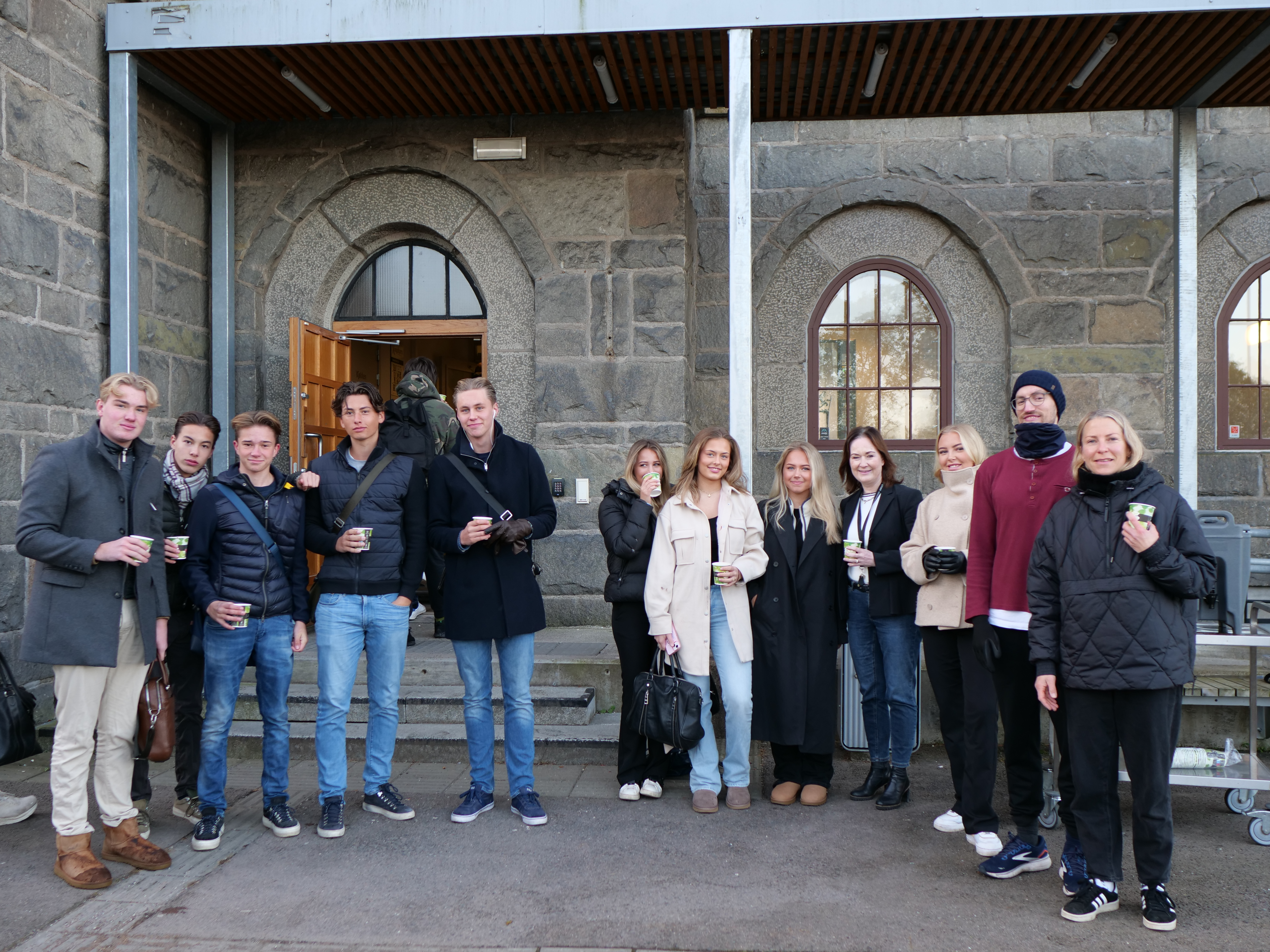 En gruppe mennesker som poserer for et bilde utenfor en bygning