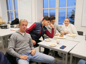 en gruppe menn som sitter ved et bord og spiser mat