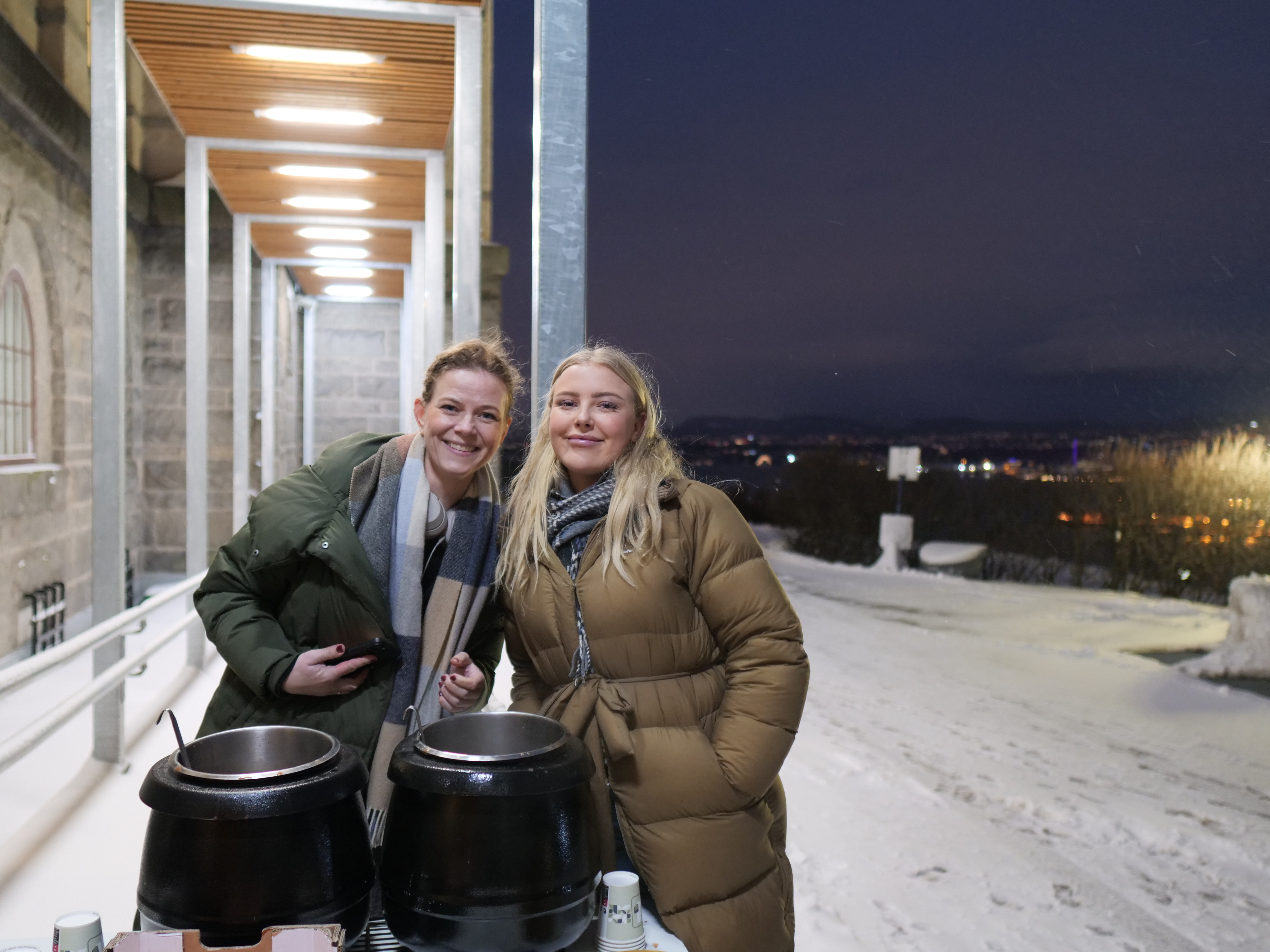 en person og person som står ved siden av en bygning med en stor metallgjenstand