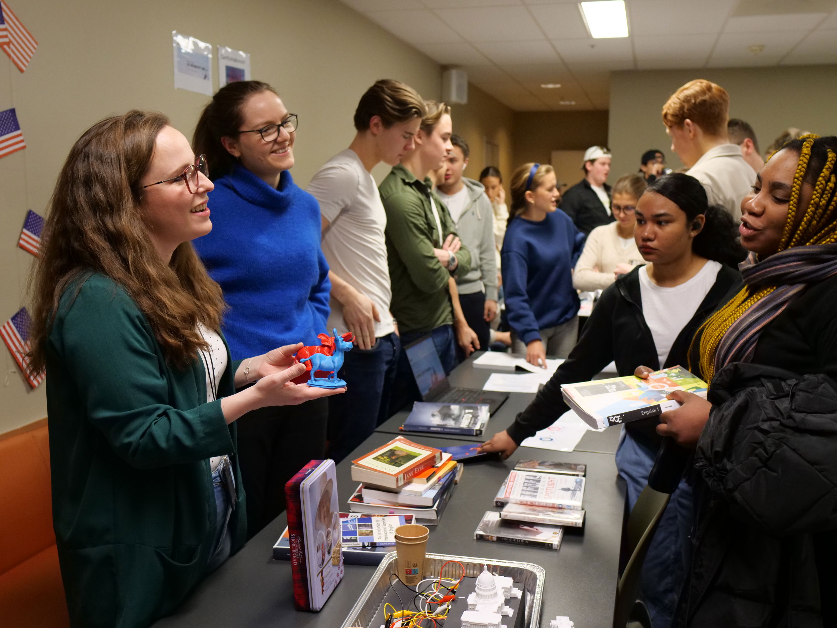 en gruppe mennesker som står rundt et bord med bøker på en gruppe mennesker som står rundt et bord med bøker på