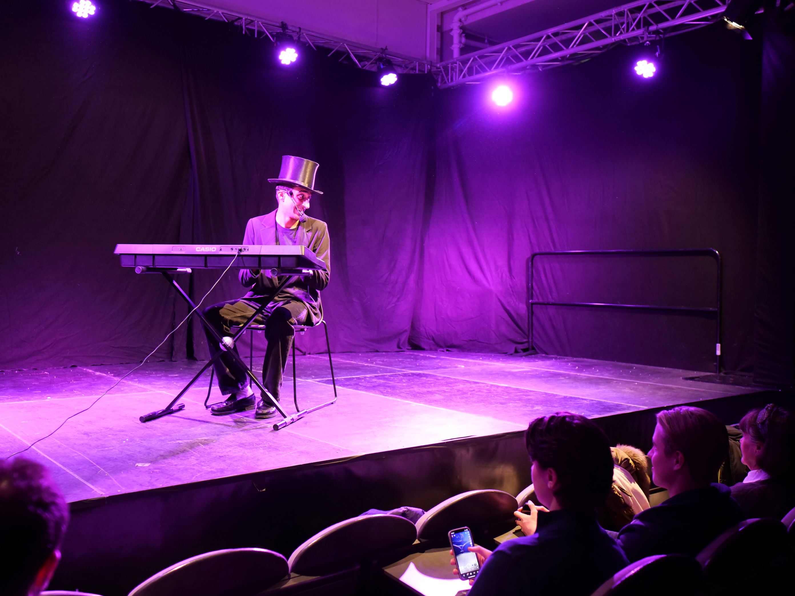 En person som spiller et keyboard på en scene med en folkemengde som ser på En person som spiller et keyboard på en scene med en folkemengde som ser på