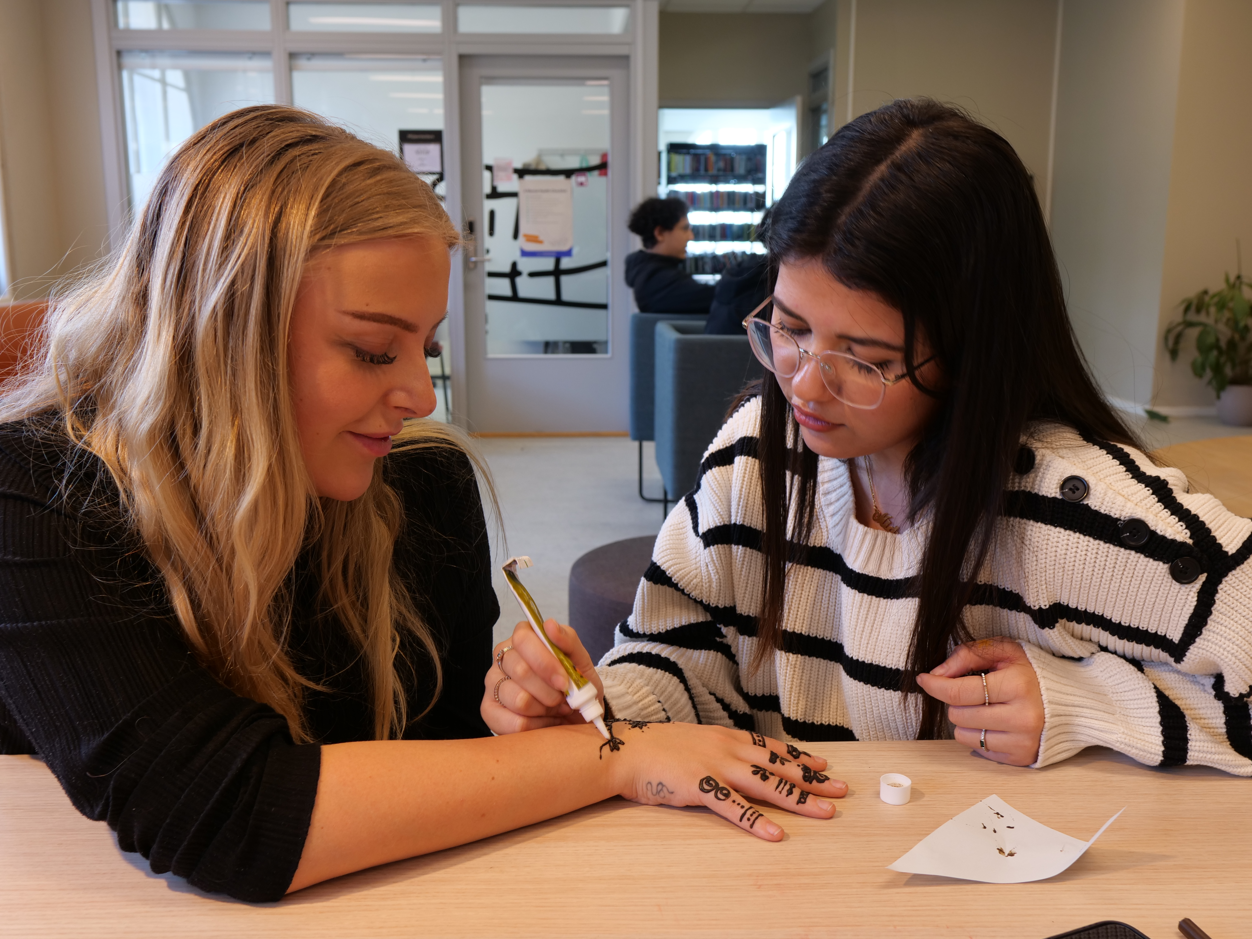 et par personr som sitter ved et bord og skriver på papir