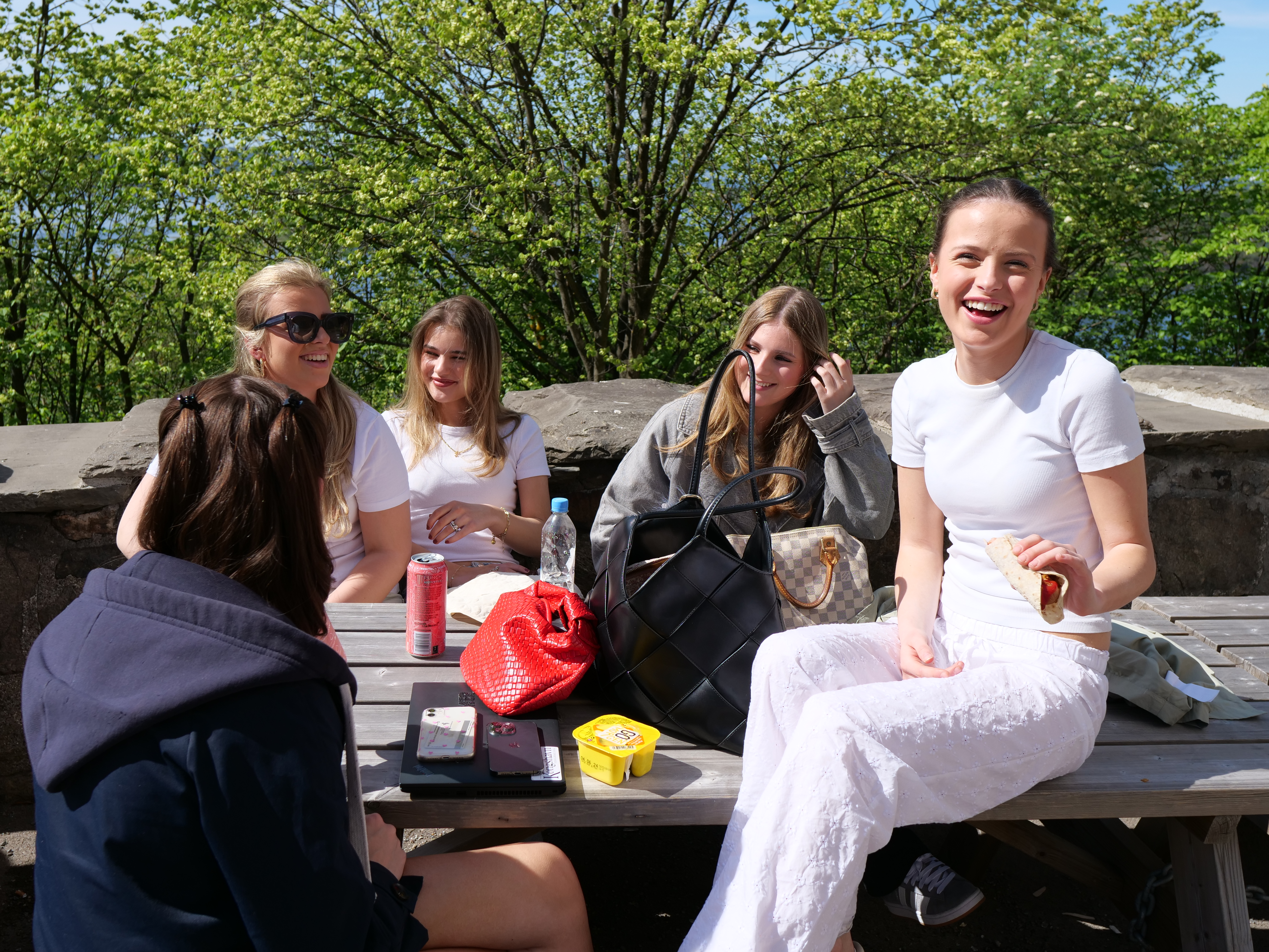 en gruppe personr som sitter ved et bord utenfor