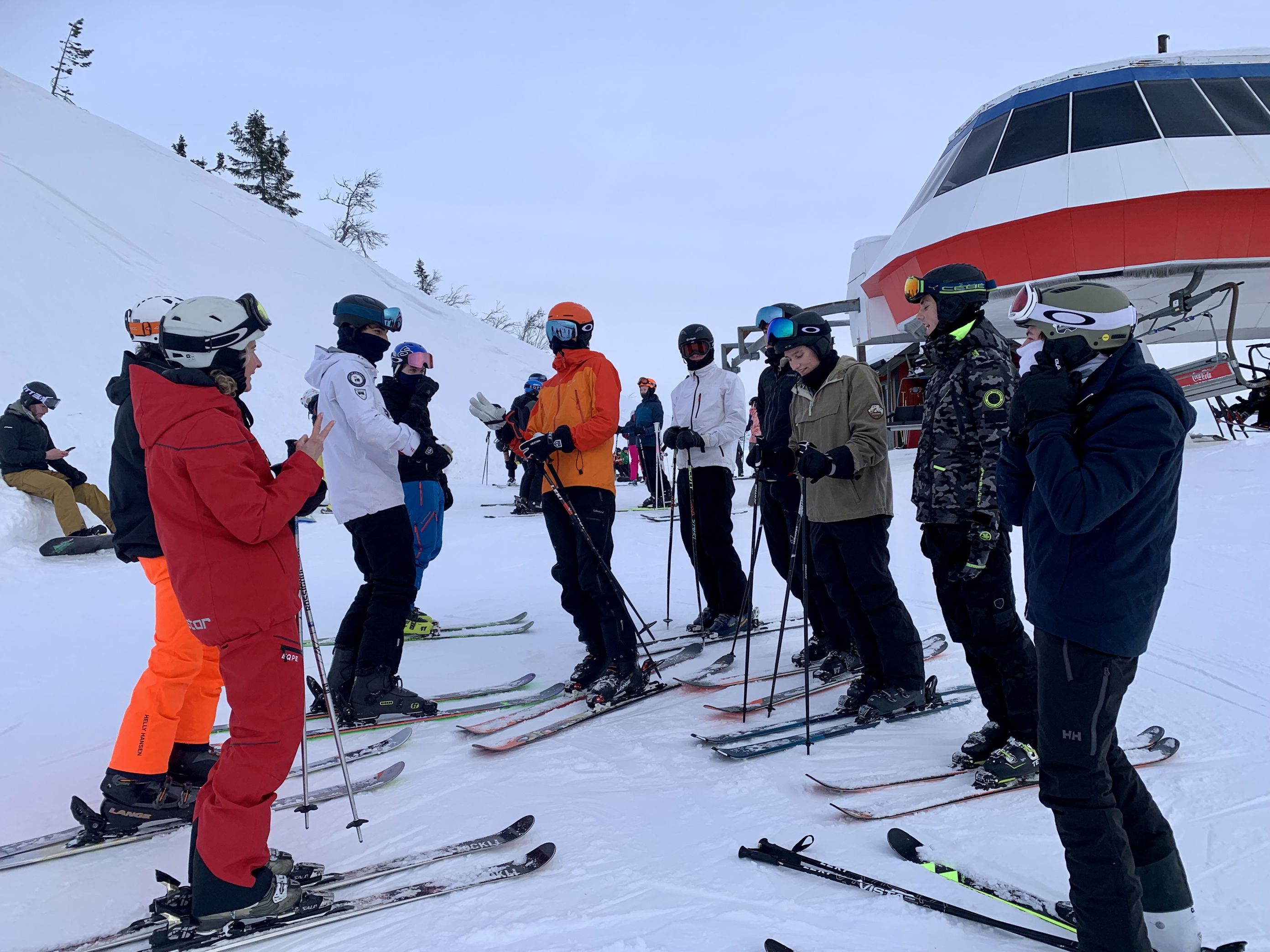 En gruppe skiløpere samler seg rundt et helikopter
