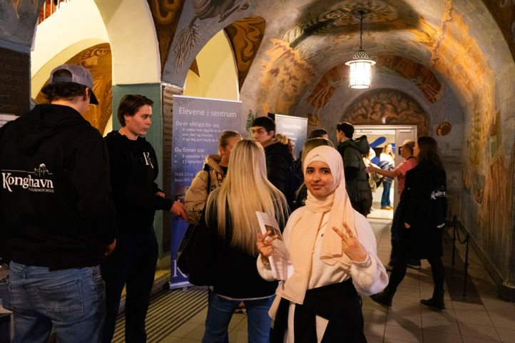 en gruppe mennesker som står i et rom med kunst på veggen