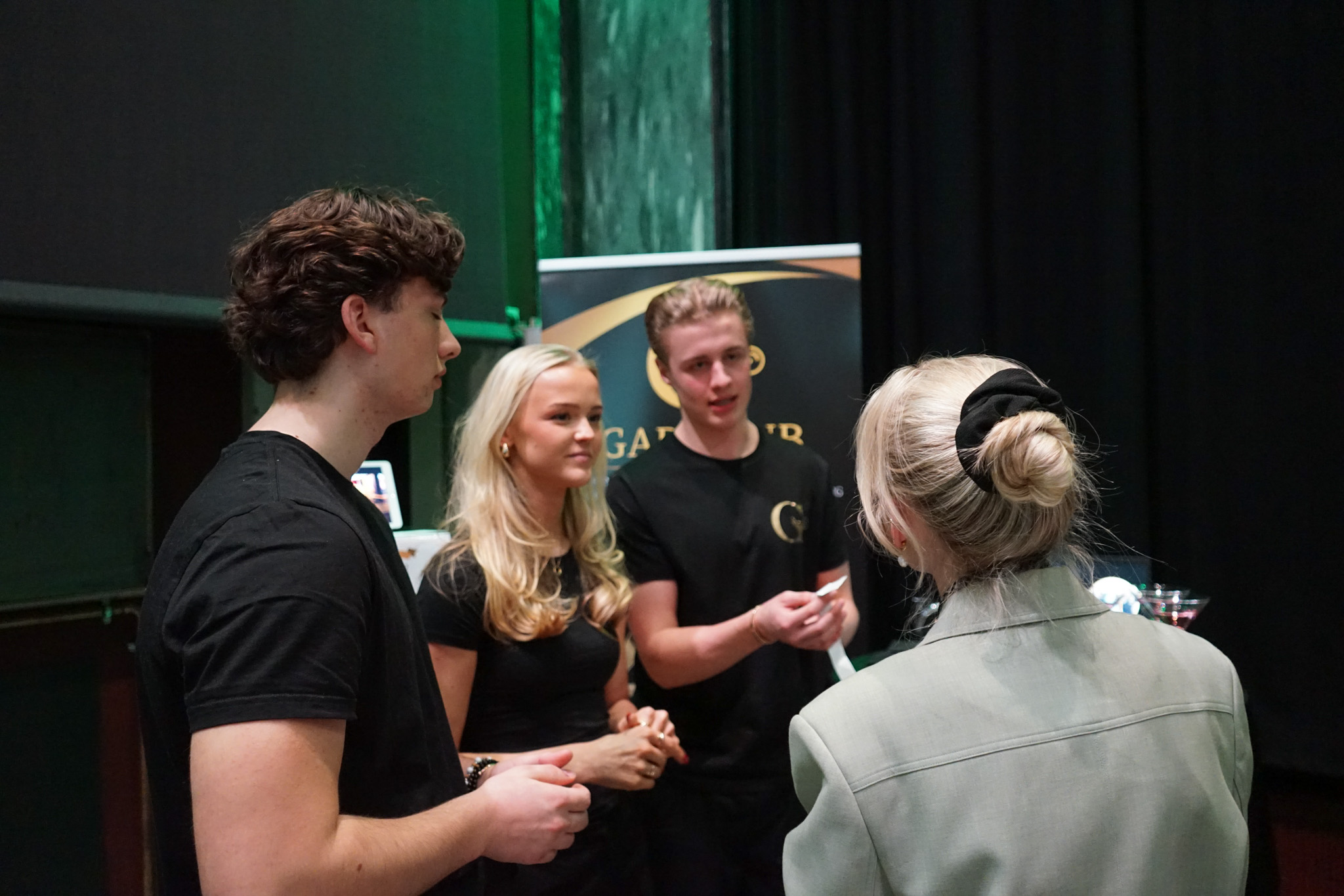 en gruppe mennesker som står foran et grønt gardin