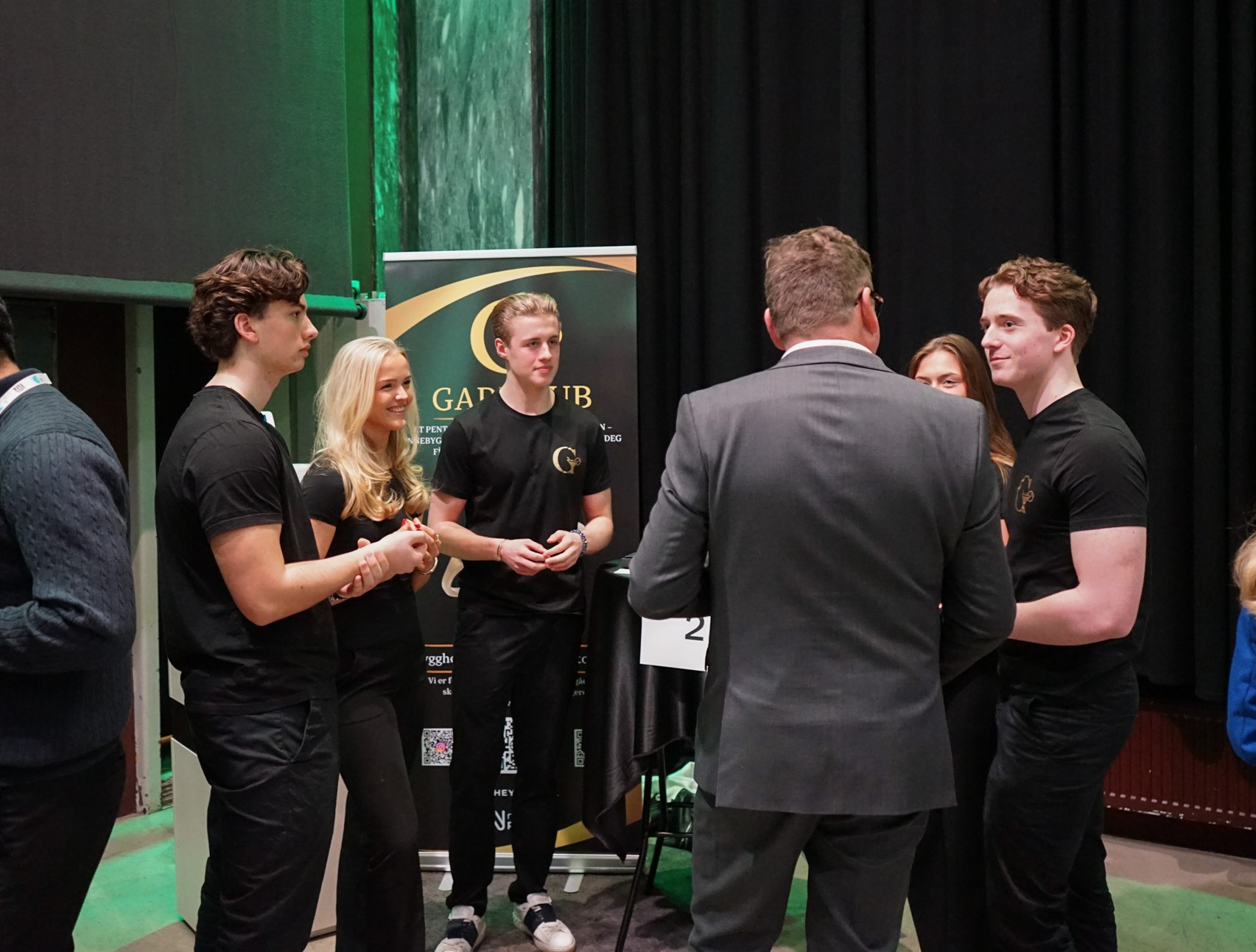 en gruppe mennesker som står foran et grønt gardin