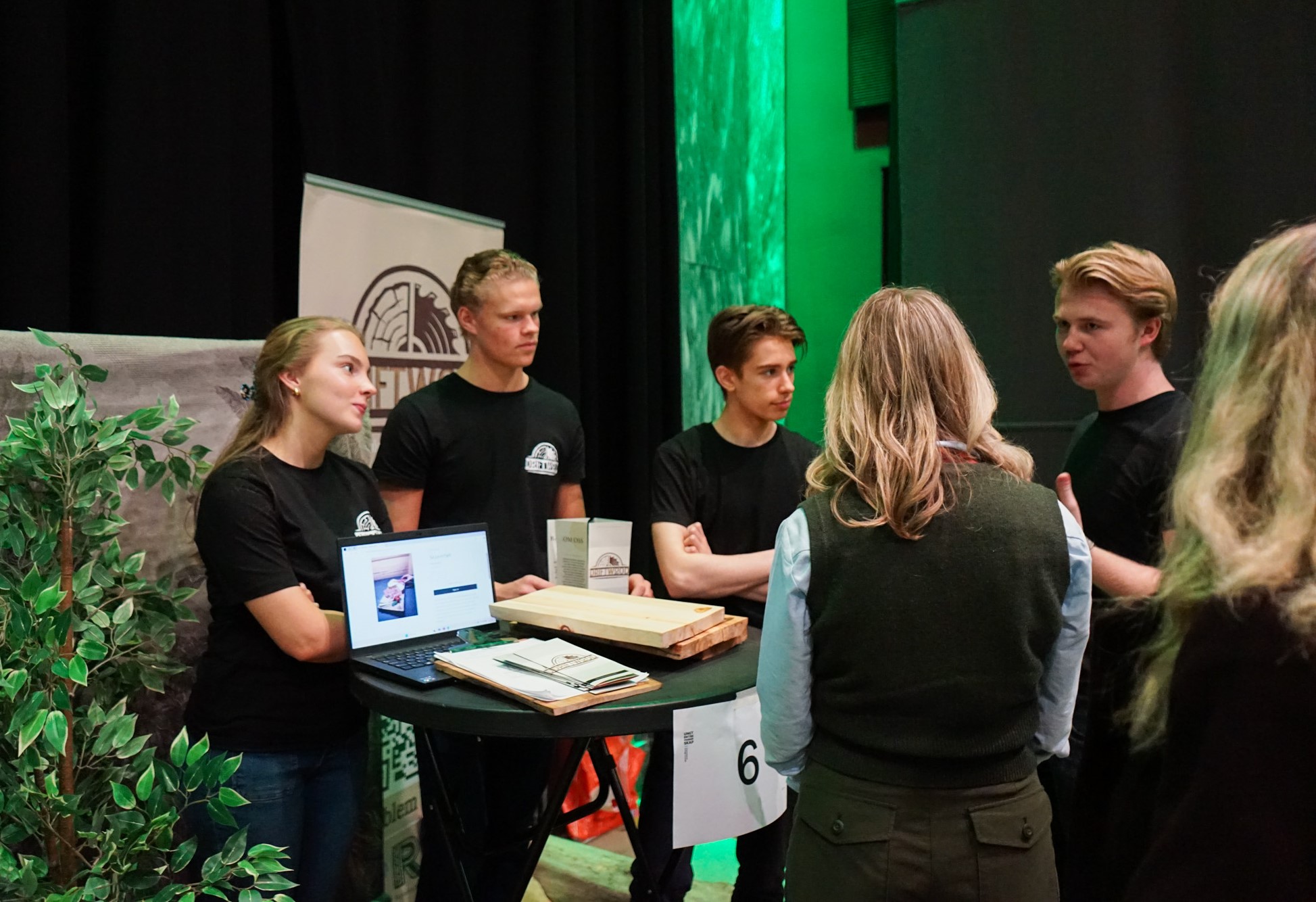 en gruppe mennesker som står rundt et bord med en bærbar datamaskin