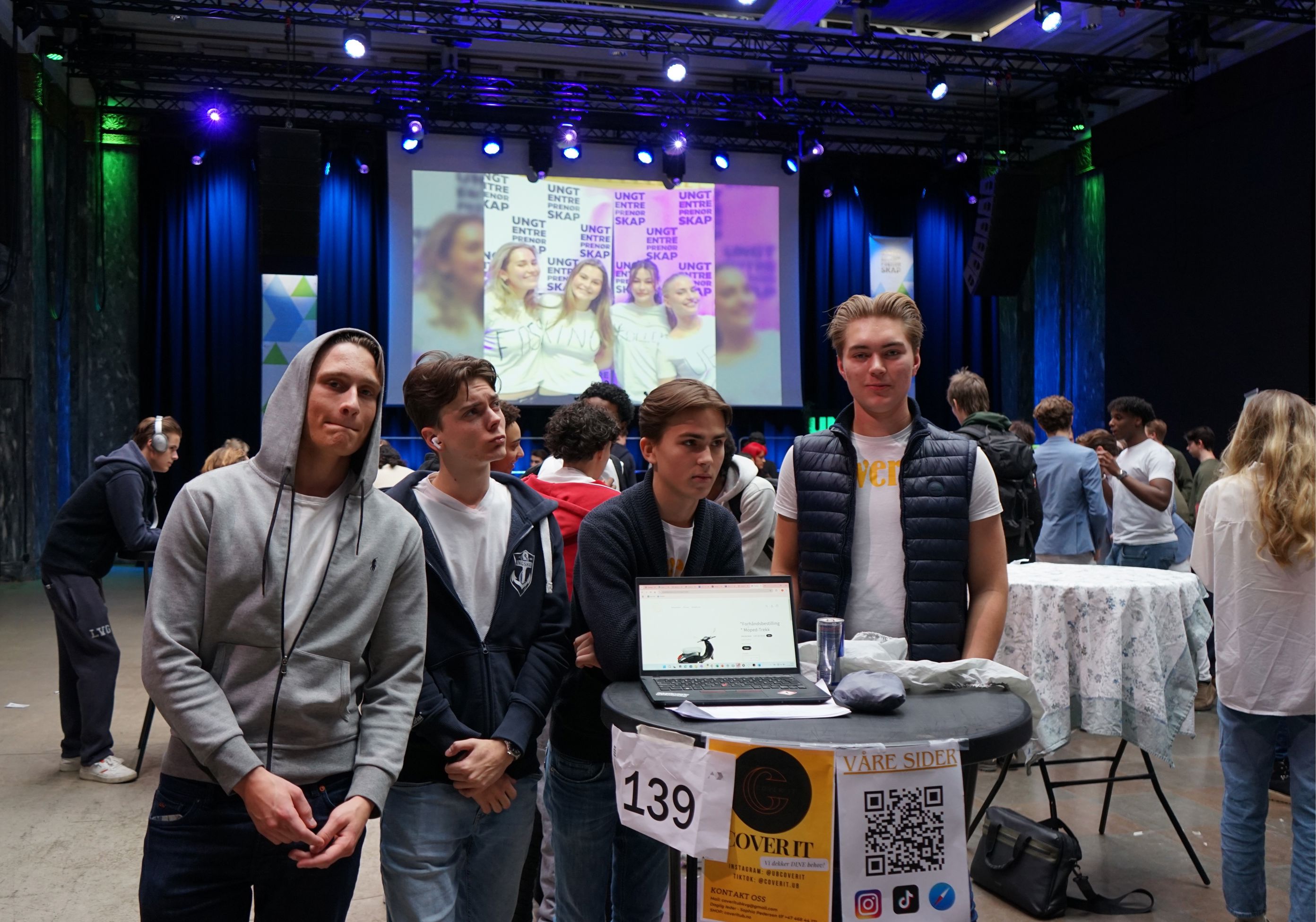 en gruppe mennesker som står rundt et bord med en bærbar datamaskin på en gruppe mennesker som står rundt et bord med en bærbar datamaskin på