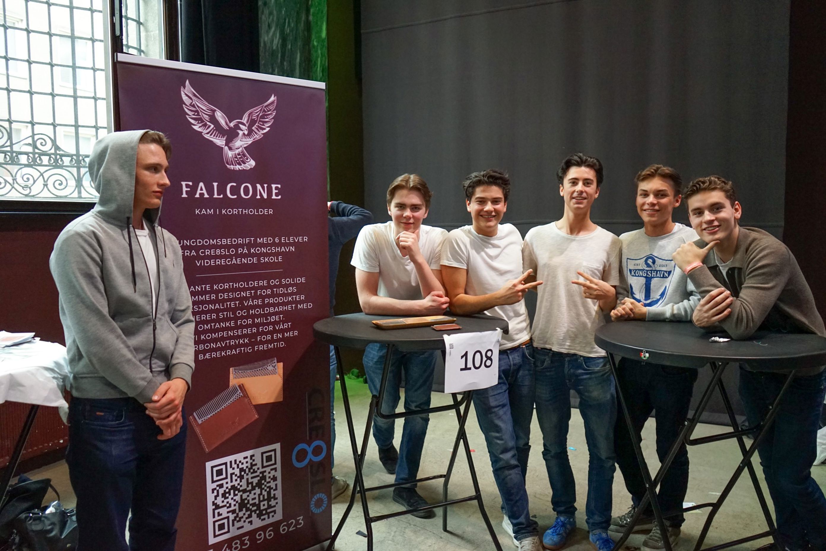 en gruppe mennesker som står ved siden av et bord med et skilt en gruppe mennesker som står ved siden av et bord med et skilt