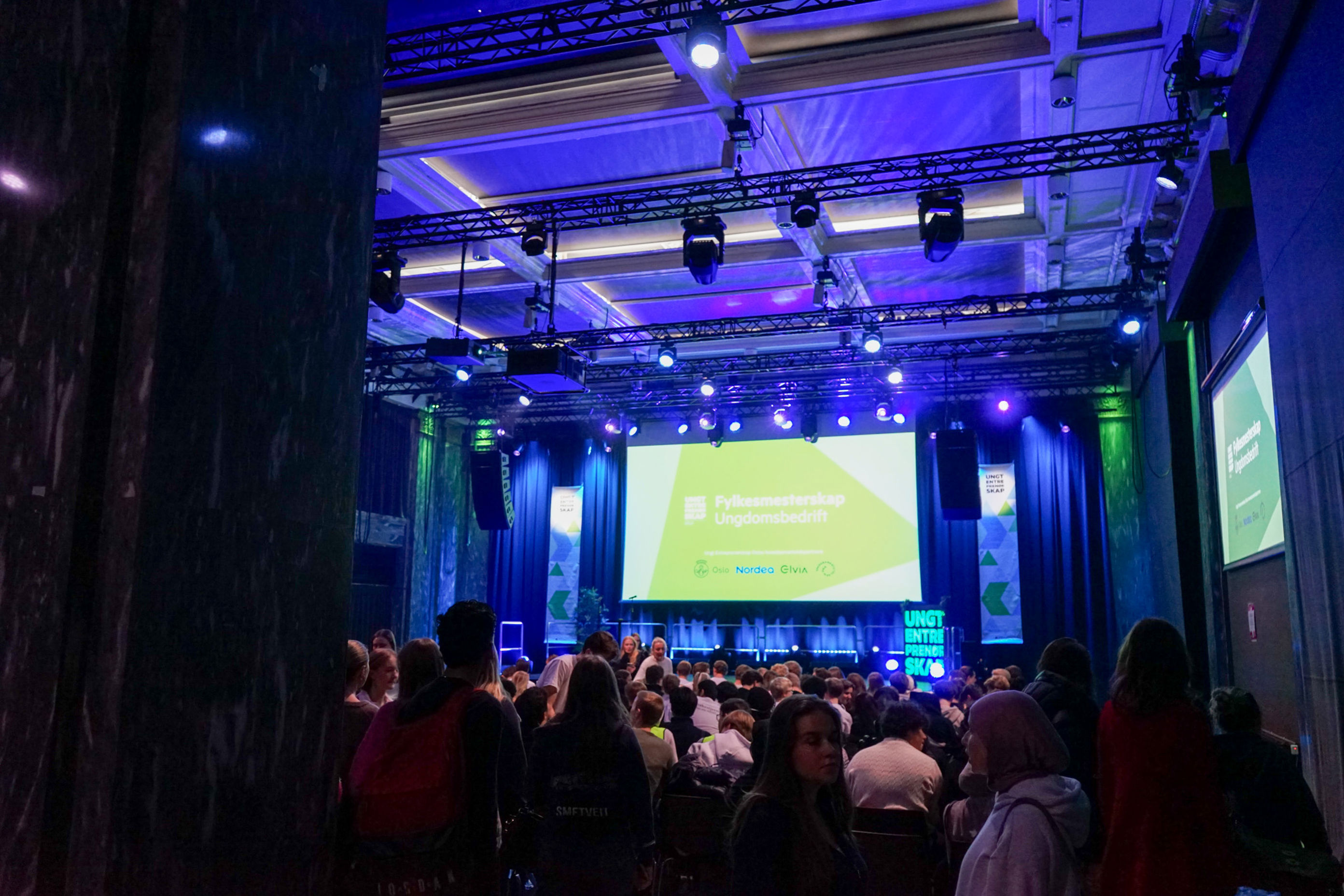 en gruppe personer i et rom med en stor skjerm en gruppe personer i et rom med en stor skjerm