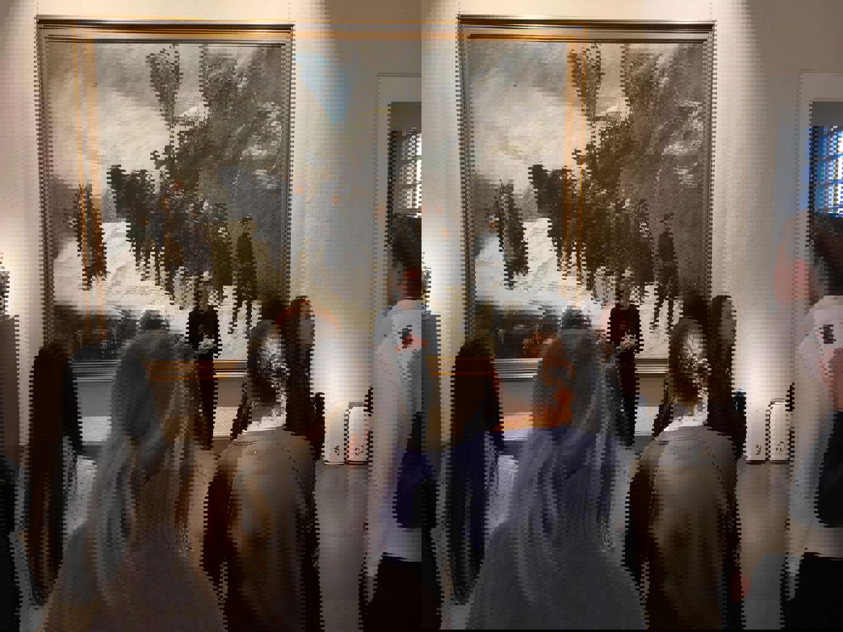 En gruppe mennesker som ser på et maleri på en vegg En gruppe mennesker som ser på et maleri på en vegg