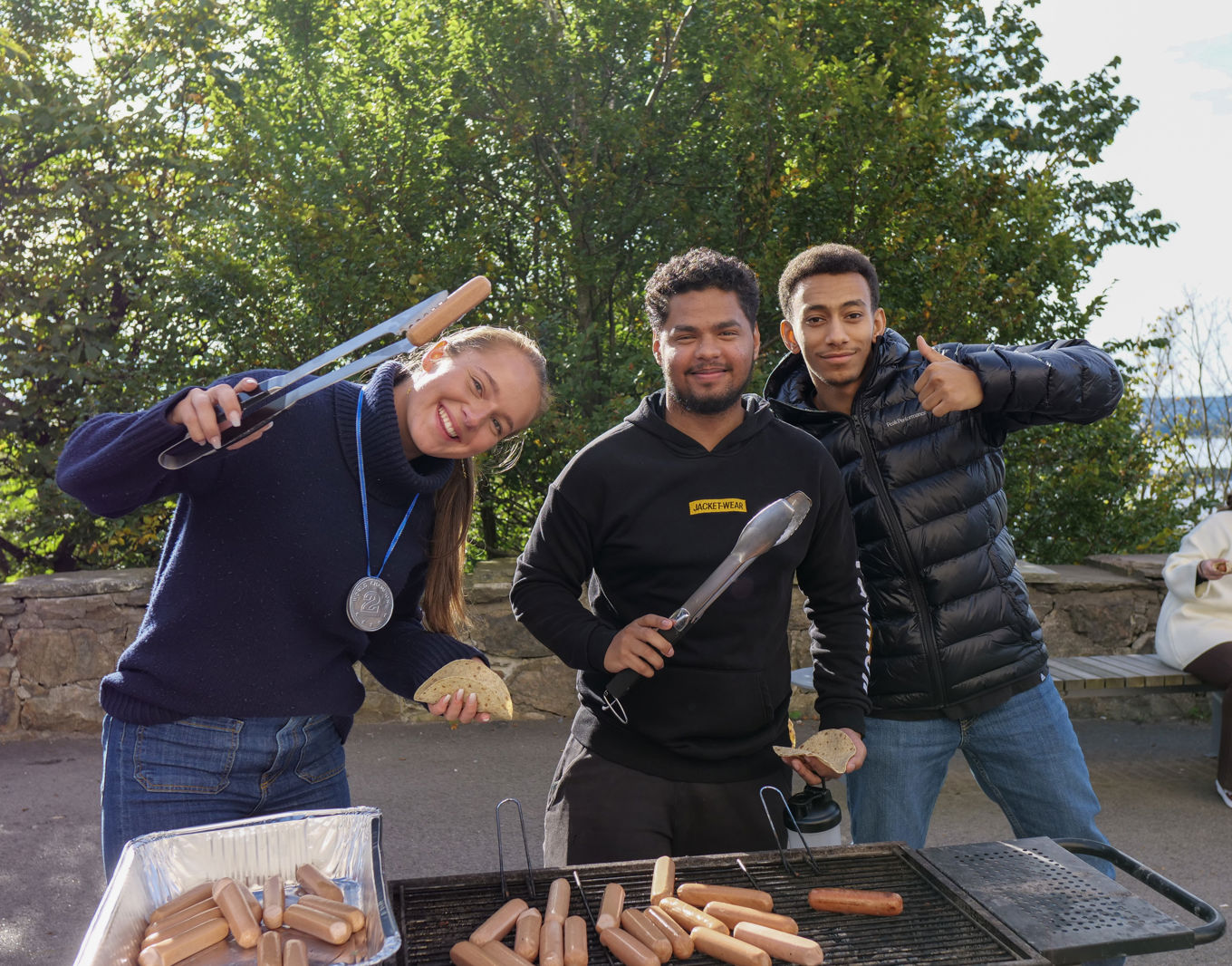 Tre elever foran en grill