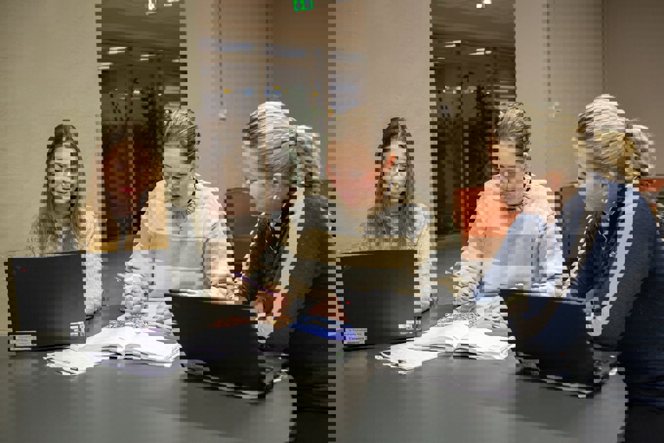 En gruppe personr som sitter ved et bord og ser på en bærbar datamaskin En gruppe personr som sitter ved et bord og ser på en bærbar datamaskin