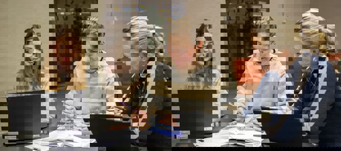 En gruppe personr som sitter ved et bord og ser på en bærbar datamaskin En gruppe personr som sitter ved et bord og ser på en bærbar datamaskin