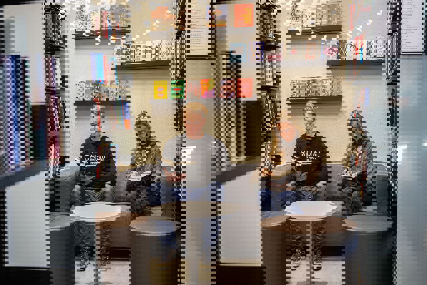 en person og en person som sitter på en sofa i et bibliotek