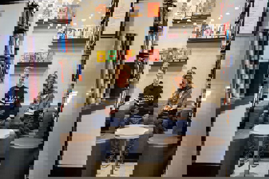 en person og en person som sitter på en sofa i et bibliotek