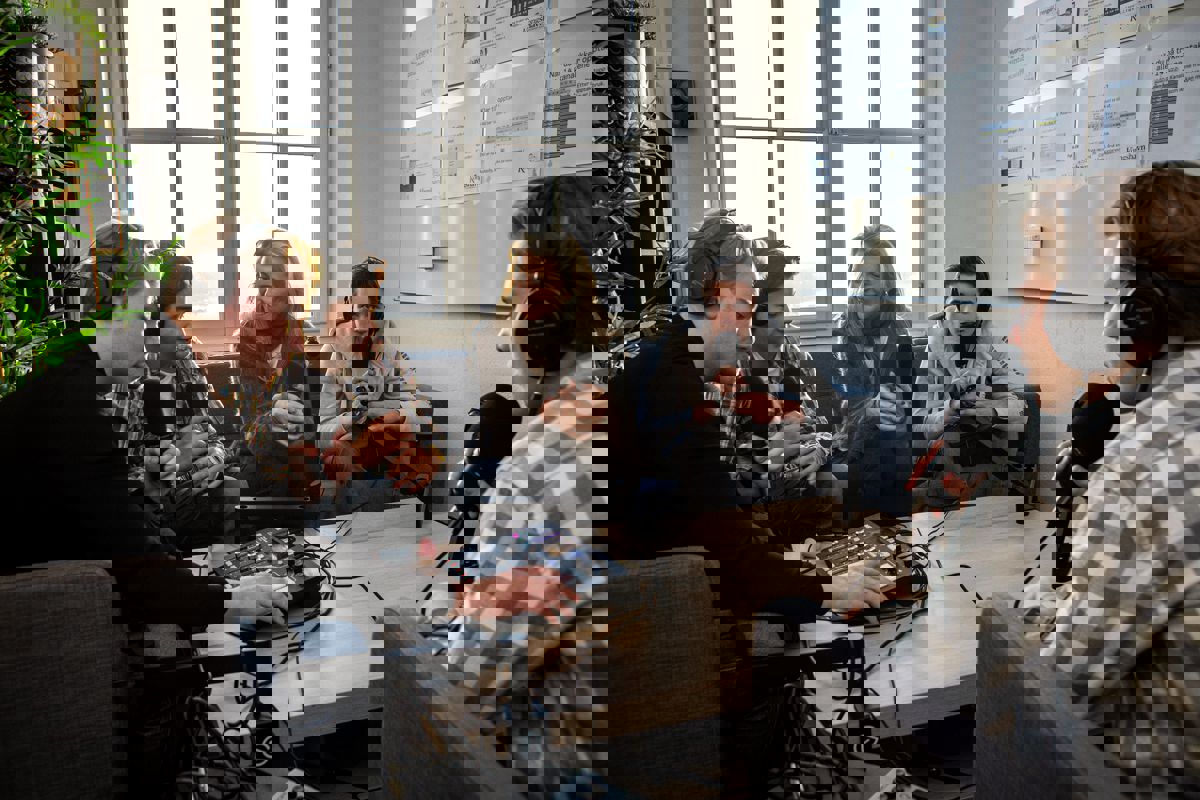 en gruppe mennesker som sitter rundt et bord med en person som står foran dem