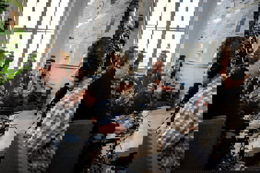 en gruppe mennesker som sitter rundt et bord med en person som står foran dem