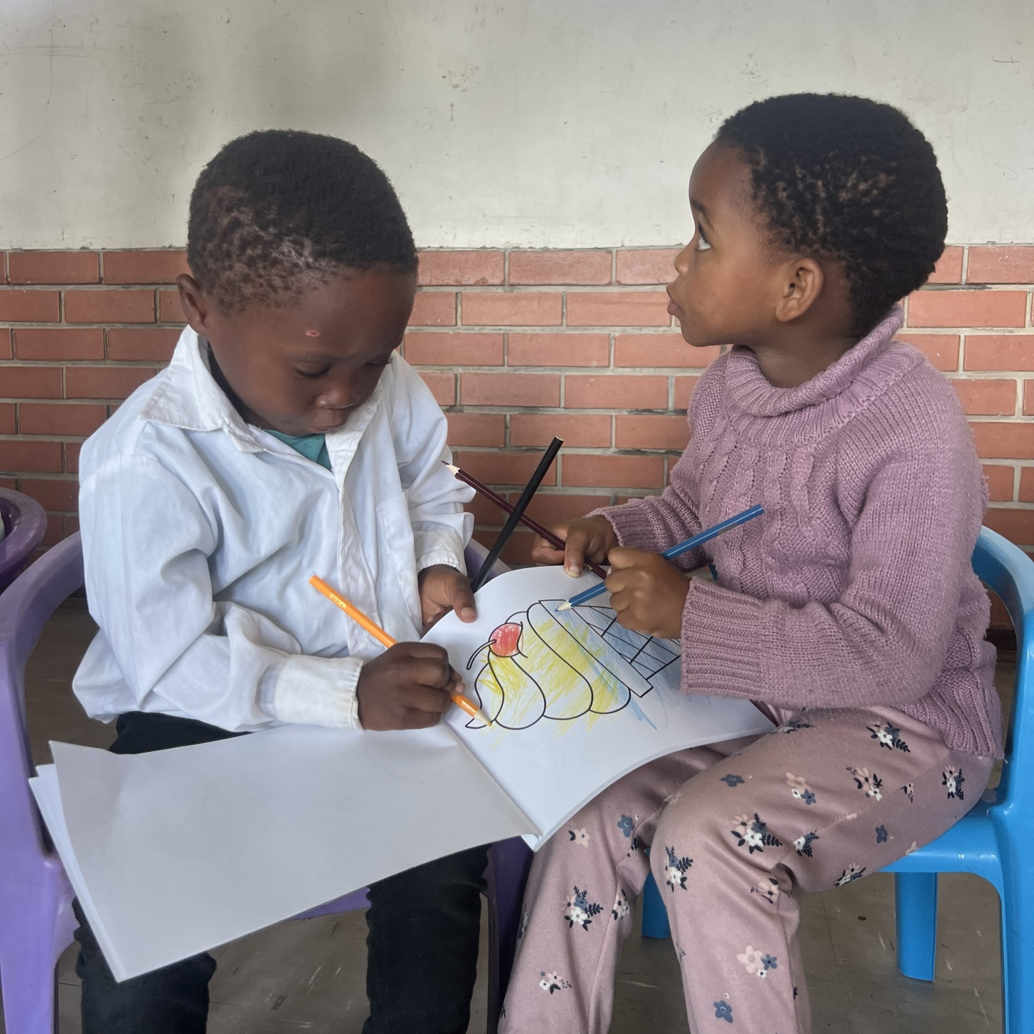 Noen små barn sitter ved et bord og maler