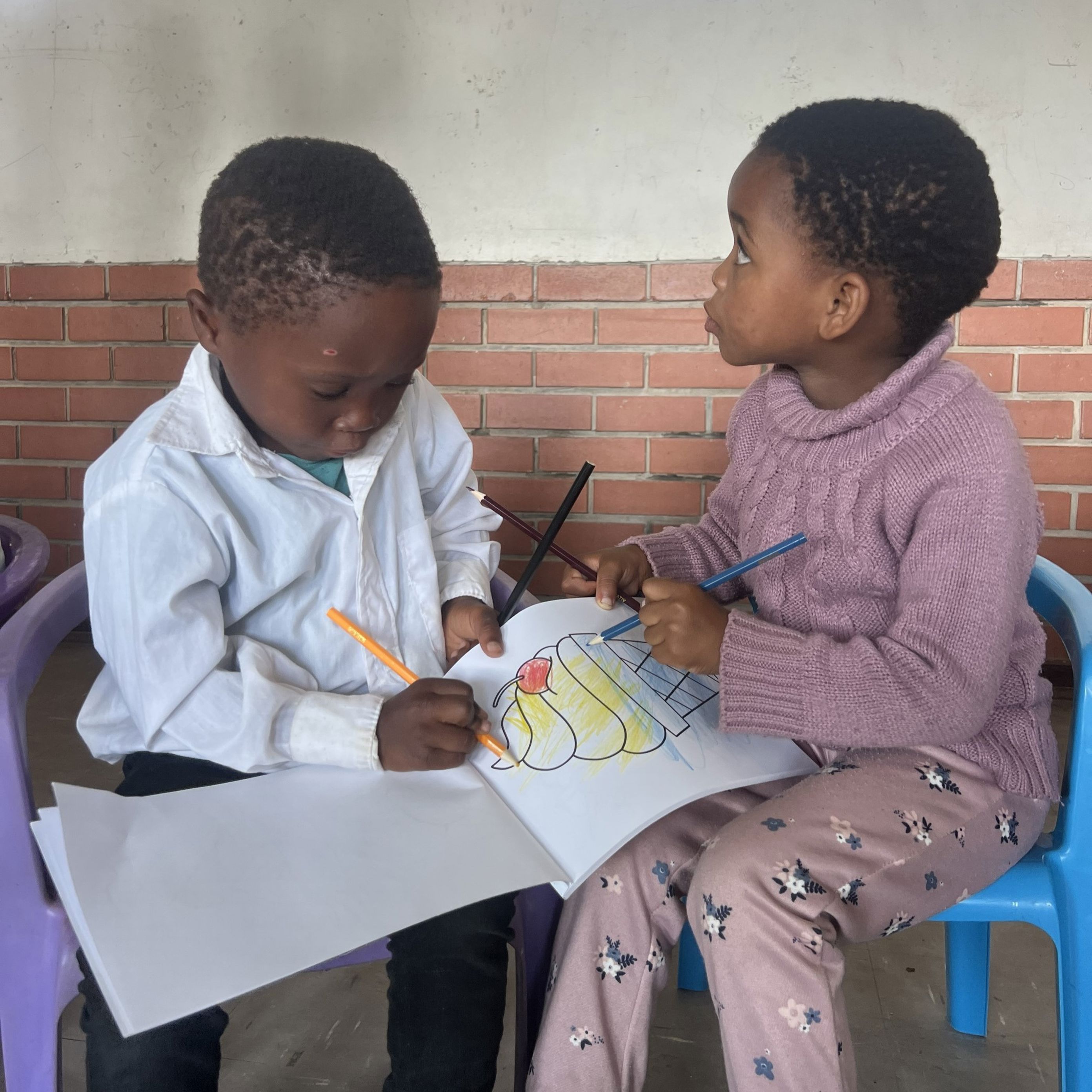 Noen små barn sitter ved et bord og maler