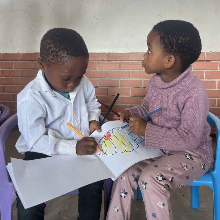 Noen små barn sitter ved et bord og maler