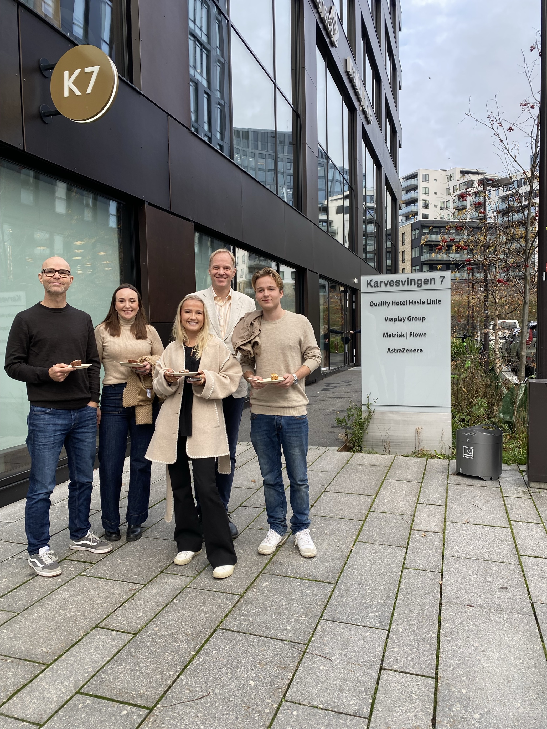 en gruppe mennesker som poserer for et bilde utenfor en bygning