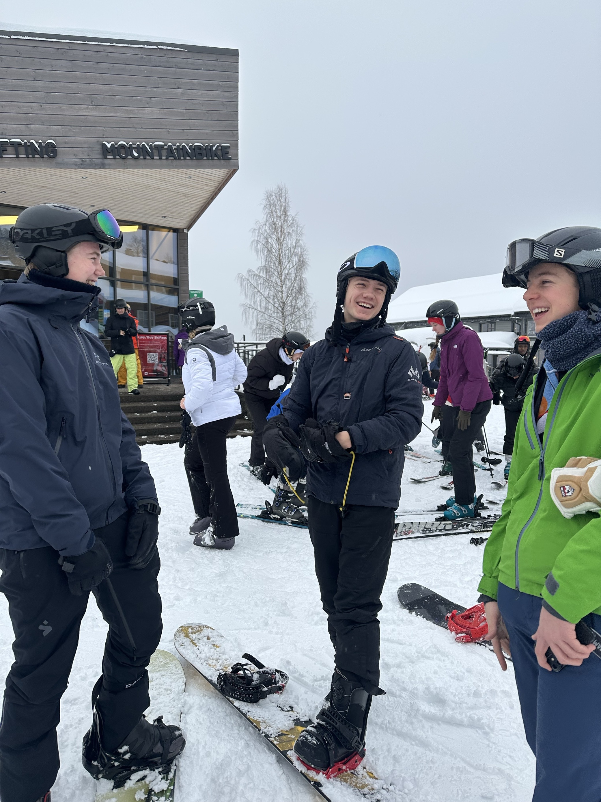 En gruppe mennesker står rundt et snowboard