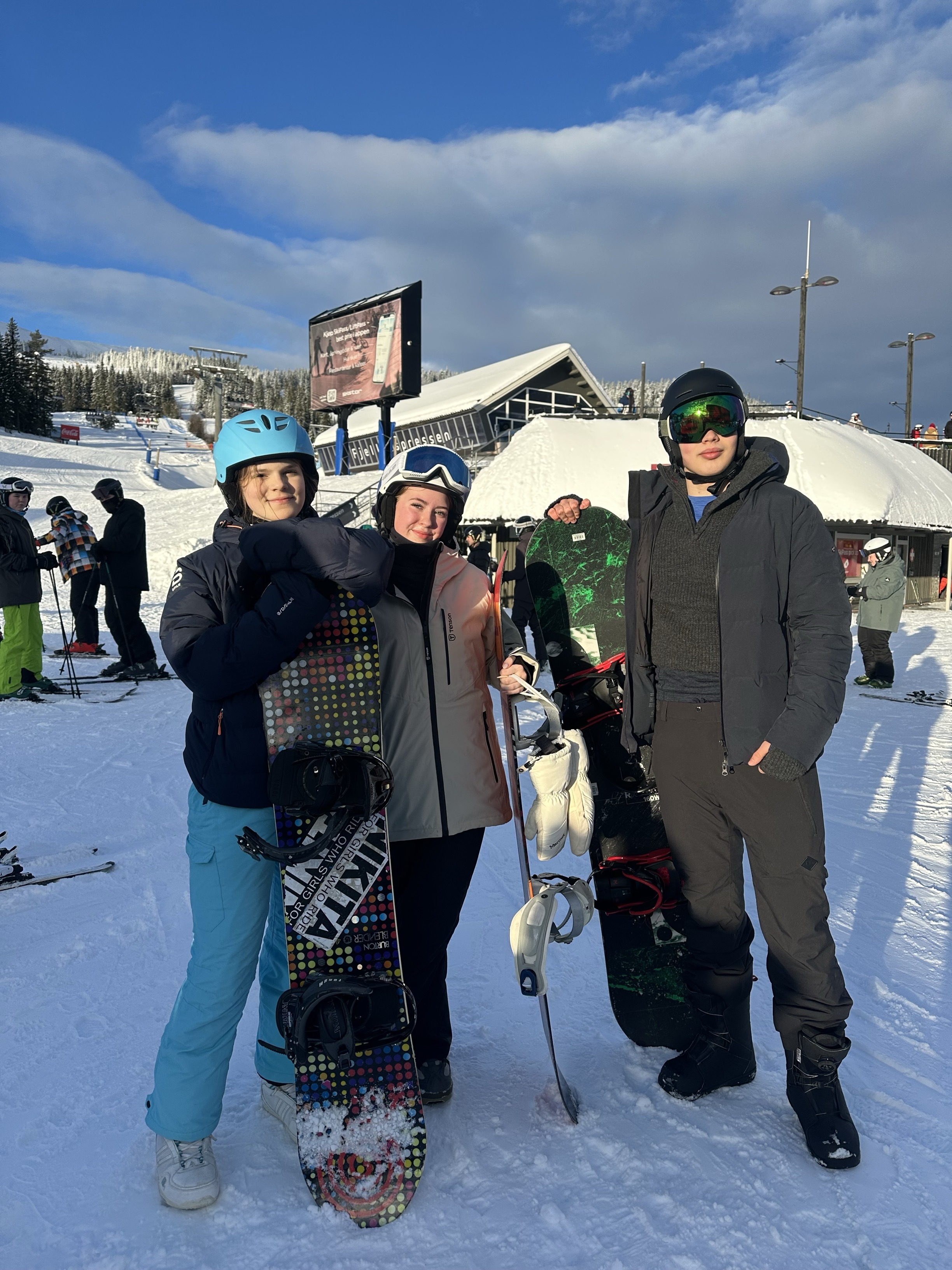 En gruppe mennesker poserer for et bilde med snowboard