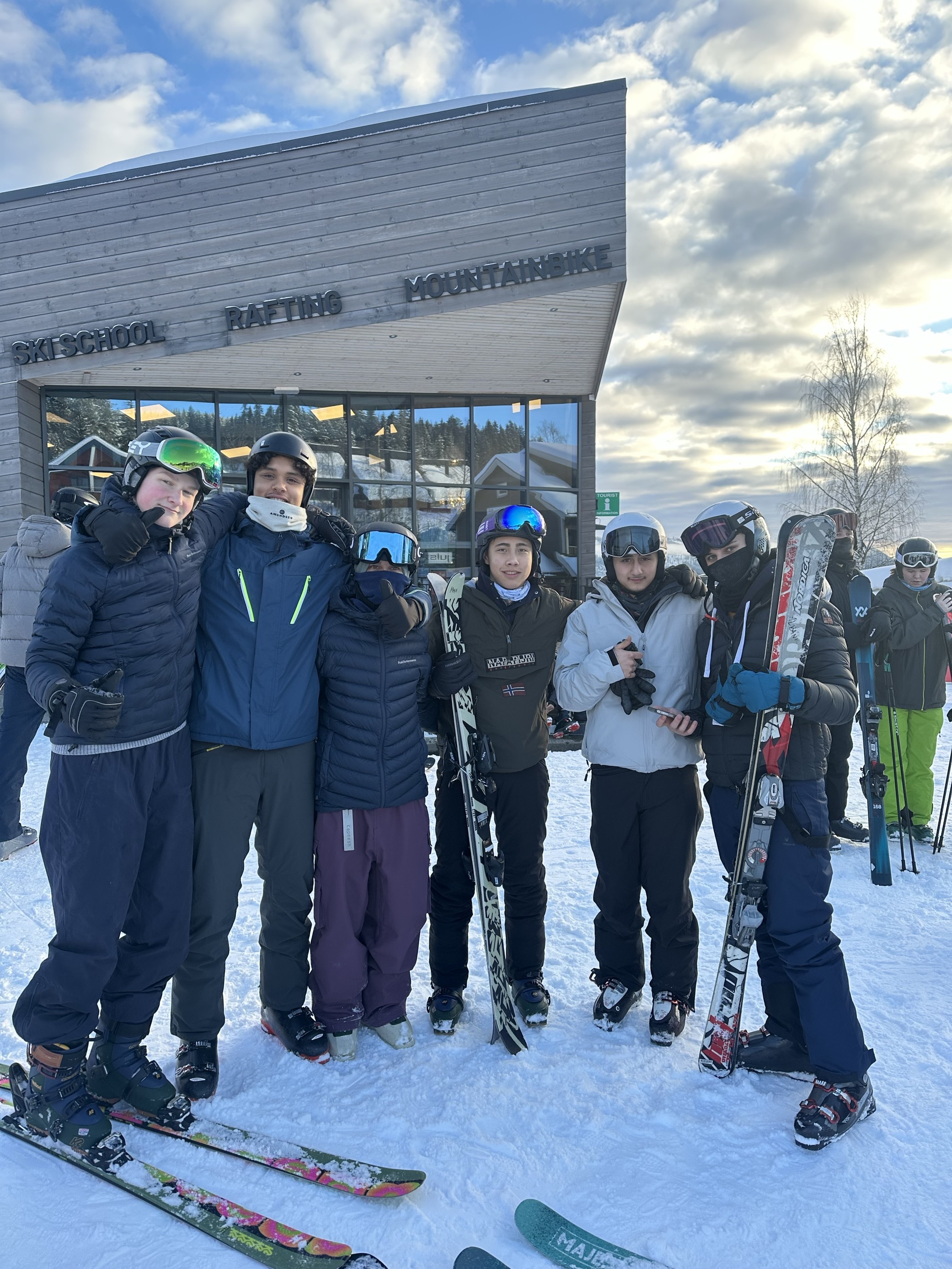 En gruppe mennesker poserer for et bilde foran en hytte