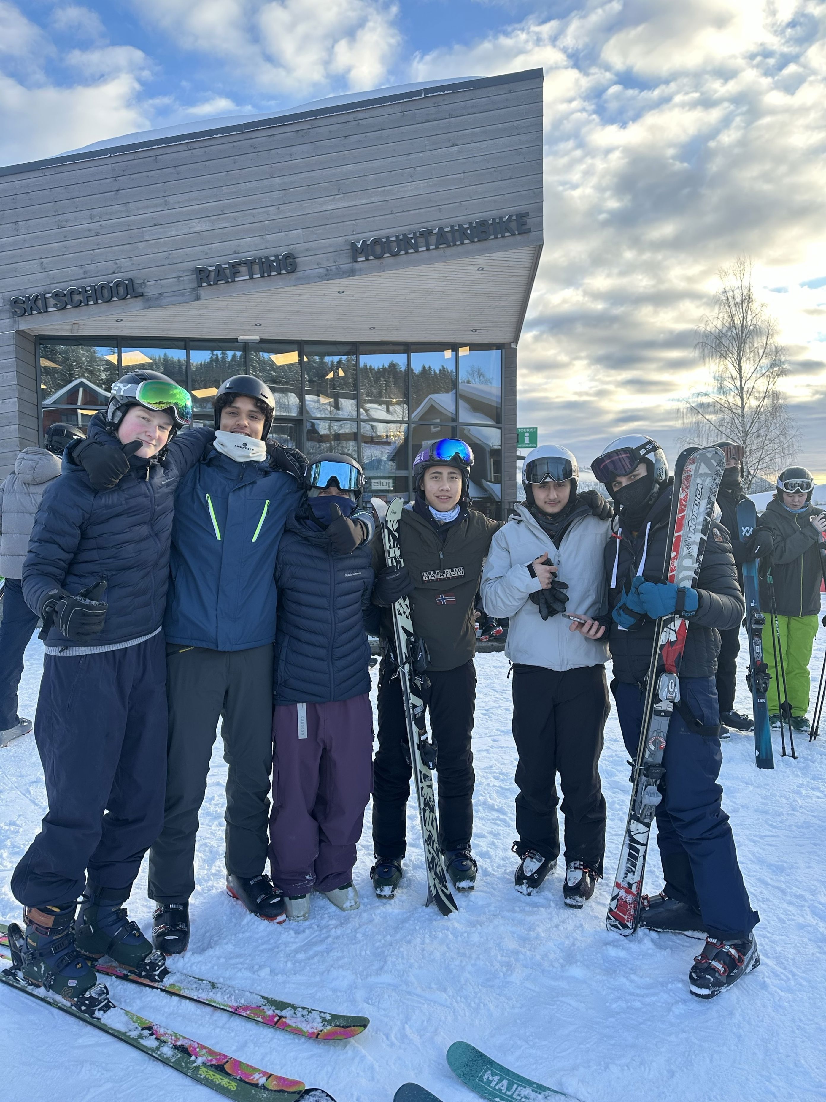 En gruppe mennesker poserer for et bilde foran en hytte En gruppe mennesker poserer for et bilde foran en hytte