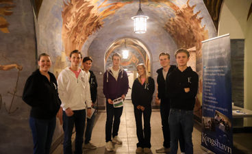 en gruppe mennesker som poserer for et bilde foran en vegg