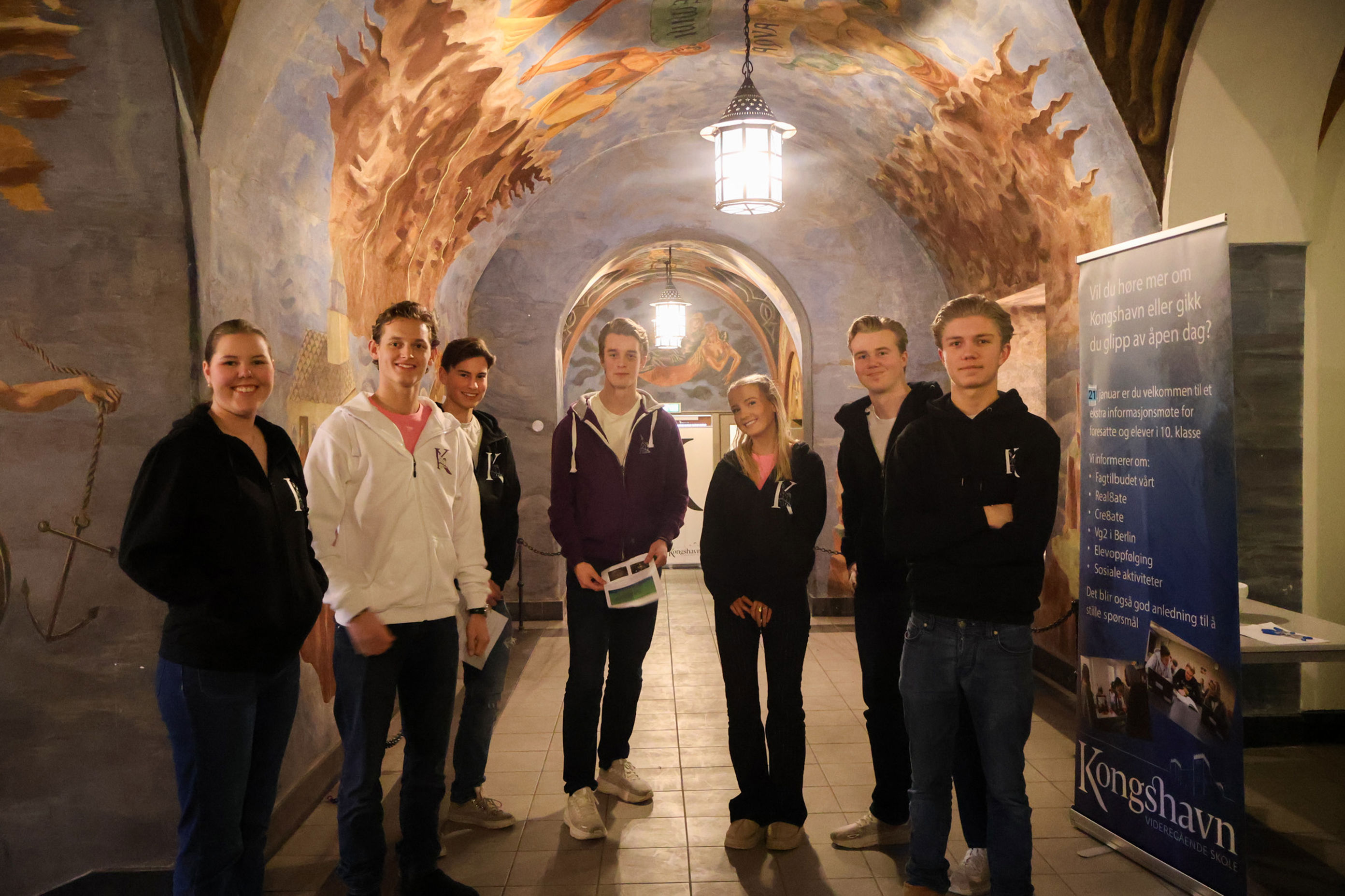 en gruppe mennesker som poserer for et bilde foran en vegg