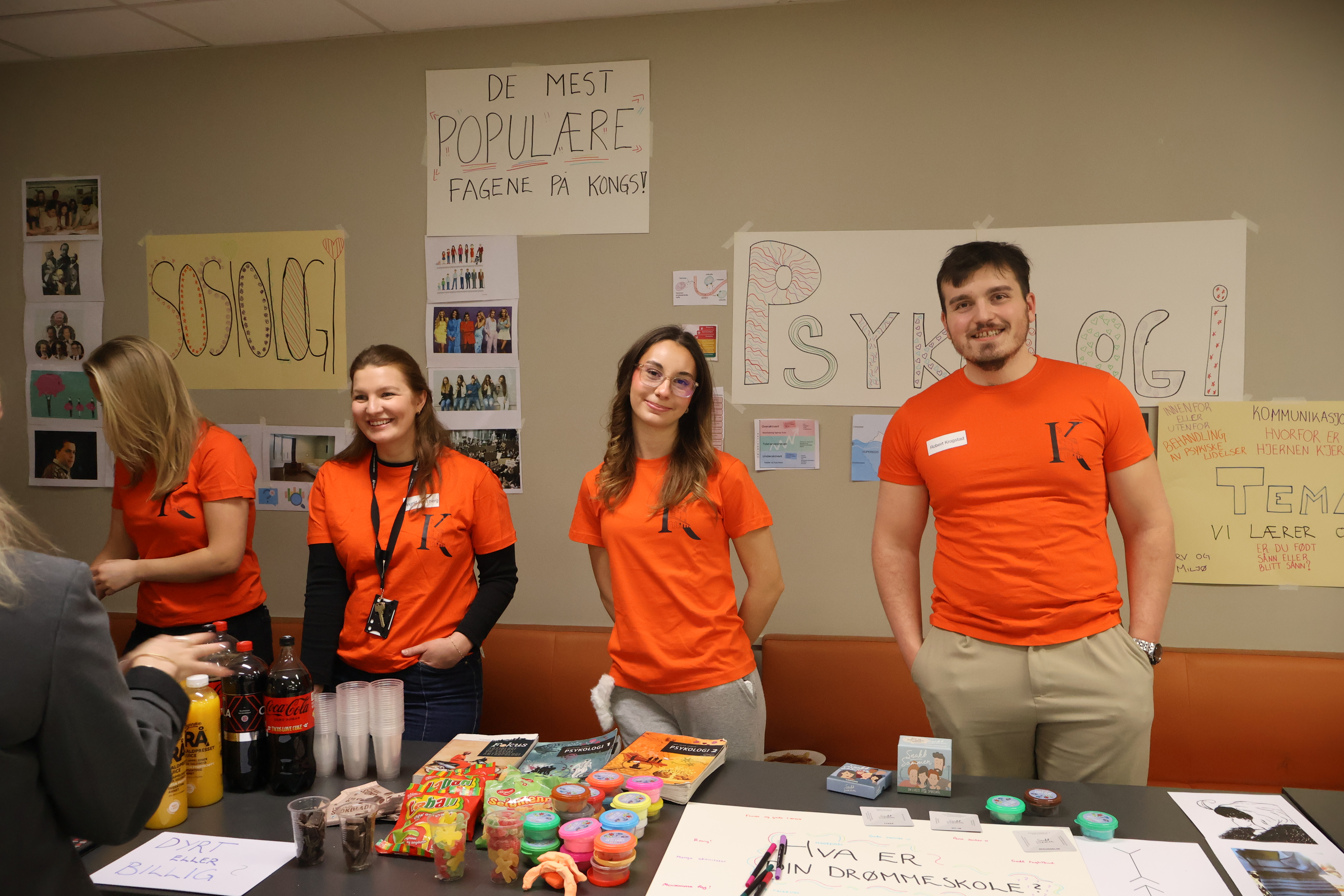 En gruppe mennesker som står foran et bord med mat og drikke