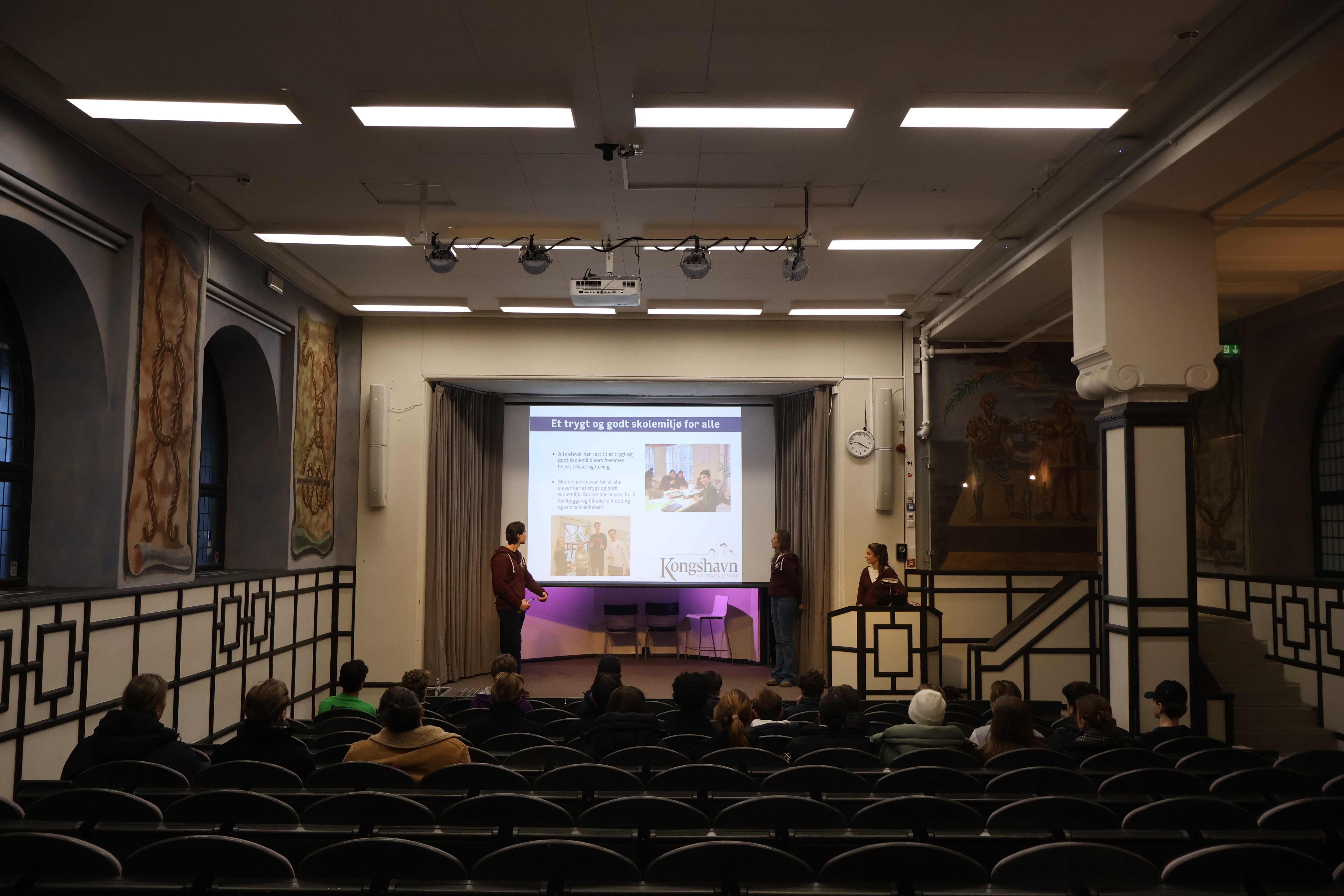 En gruppe mennesker i et rom med projektorskjerm