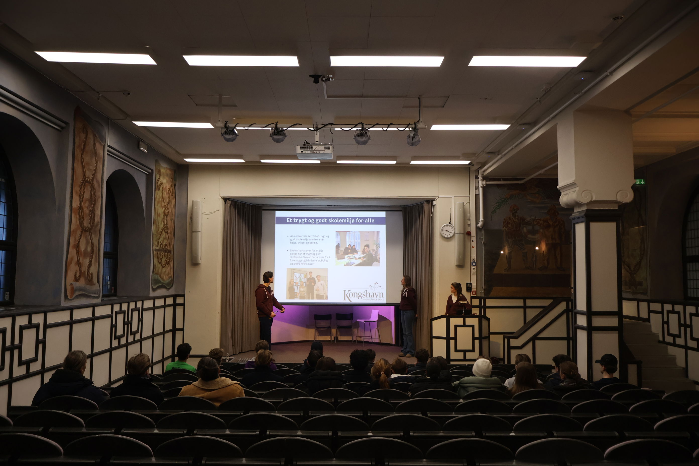 En gruppe mennesker i et rom med projektorskjerm