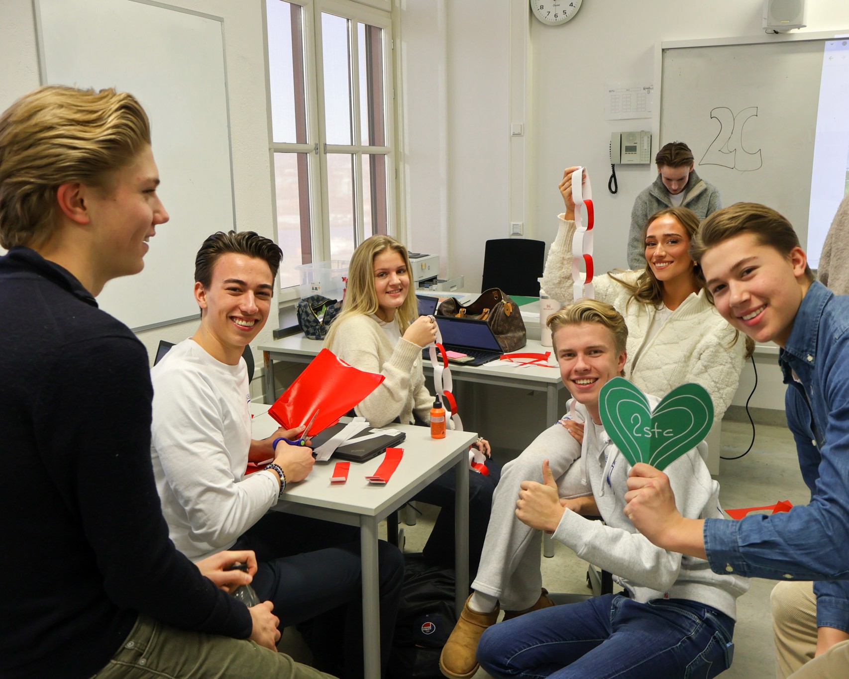 En gruppe mennesker som satt ved pulter og smilte