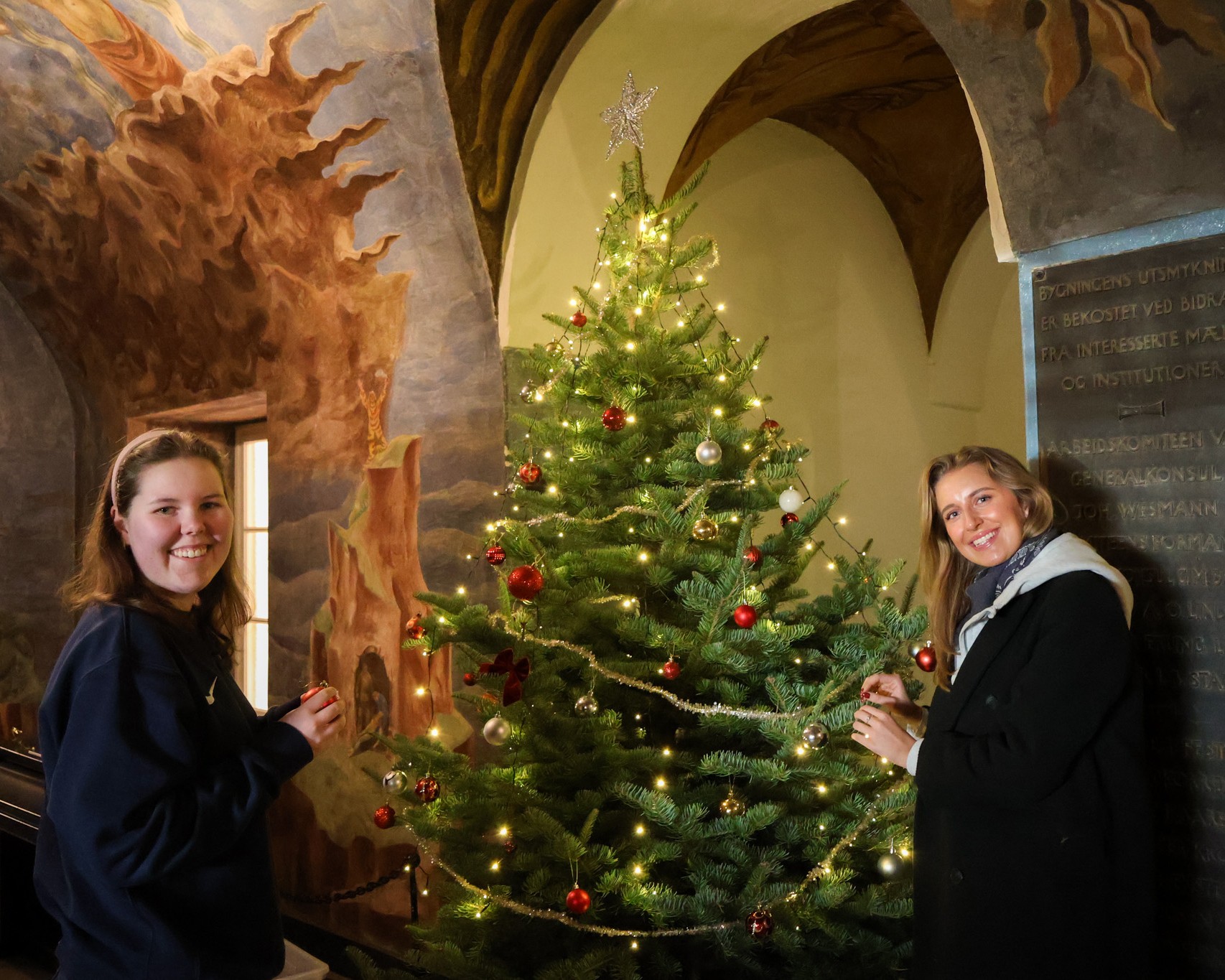 Et par personr som står ved siden av et juletre