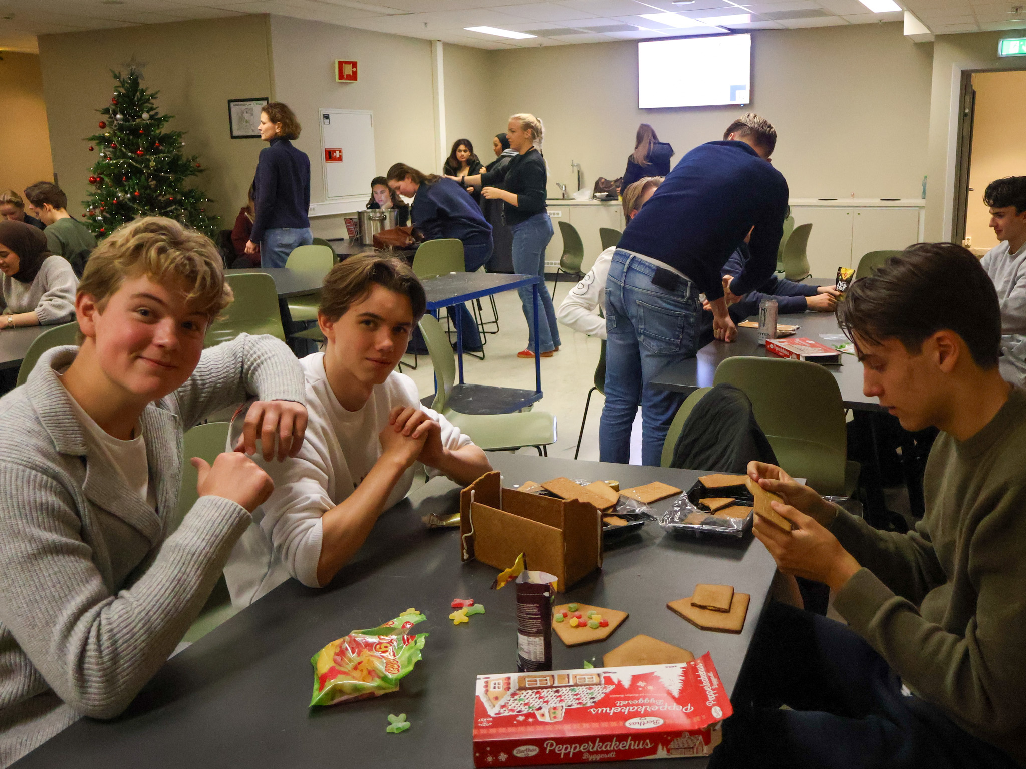 En gruppe mennesker sitter ved et bord med esker med kjeks