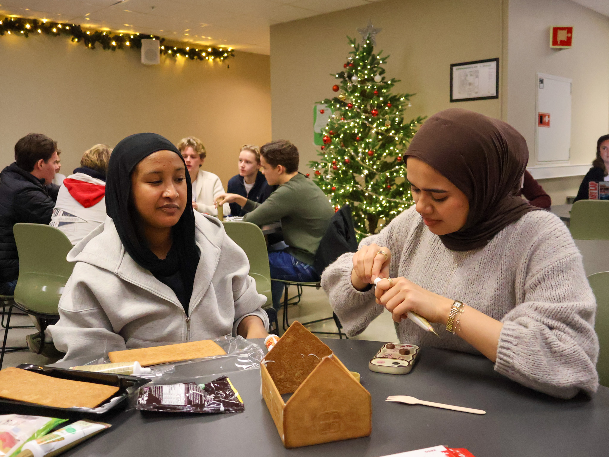 En gruppe mennesker som sitter ved et bord med mat og et juletre