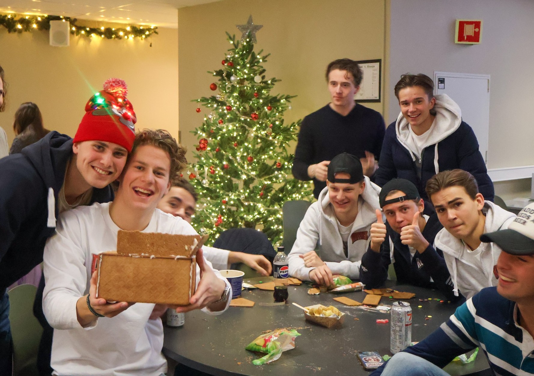 En gruppe mennesker som sitter rundt et bord med mat og et juletre