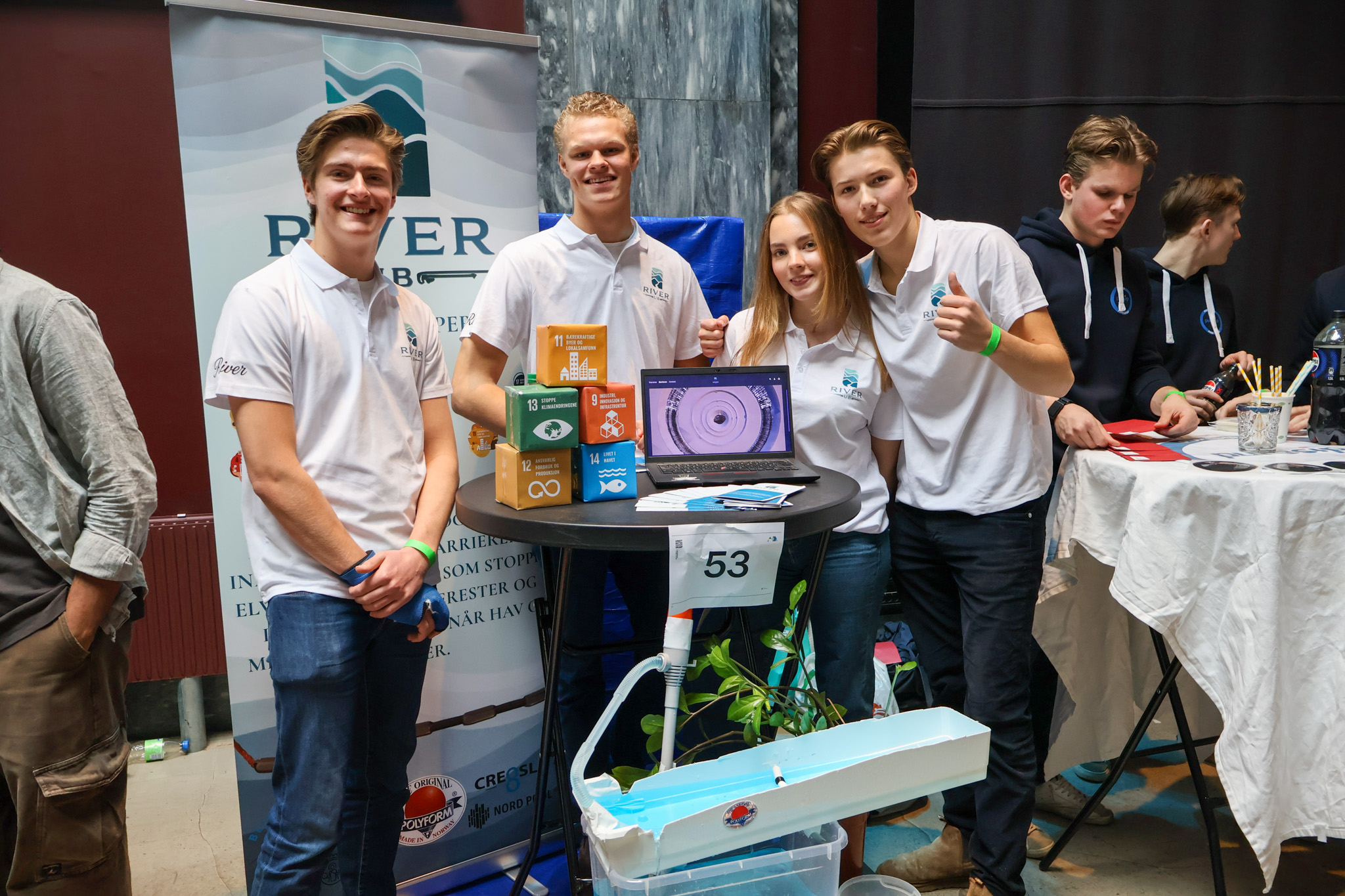 en gruppe mennesker som står rundt et bord med en bærbar PC