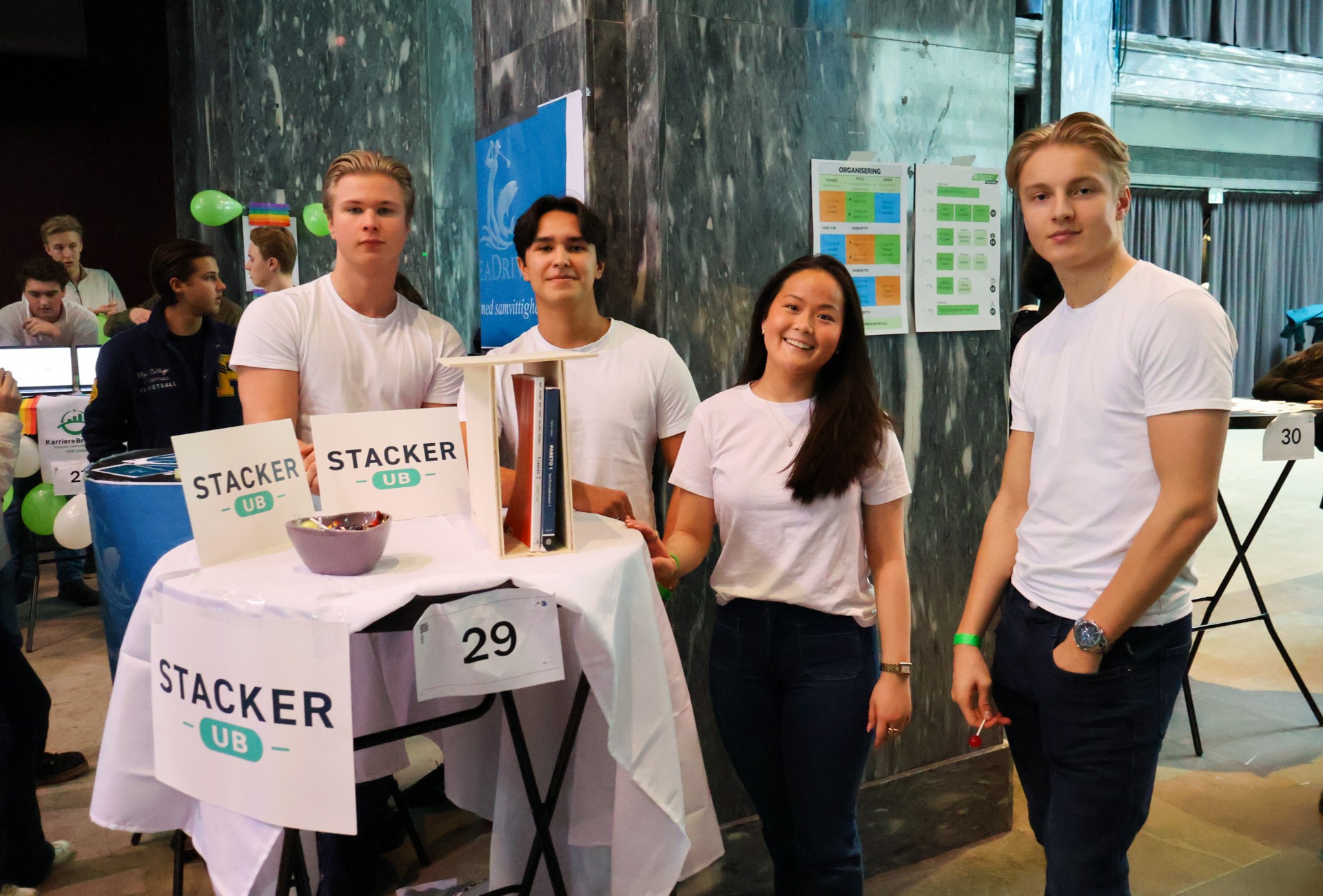 en gruppe mennesker som står ved siden av et bord med et skilt