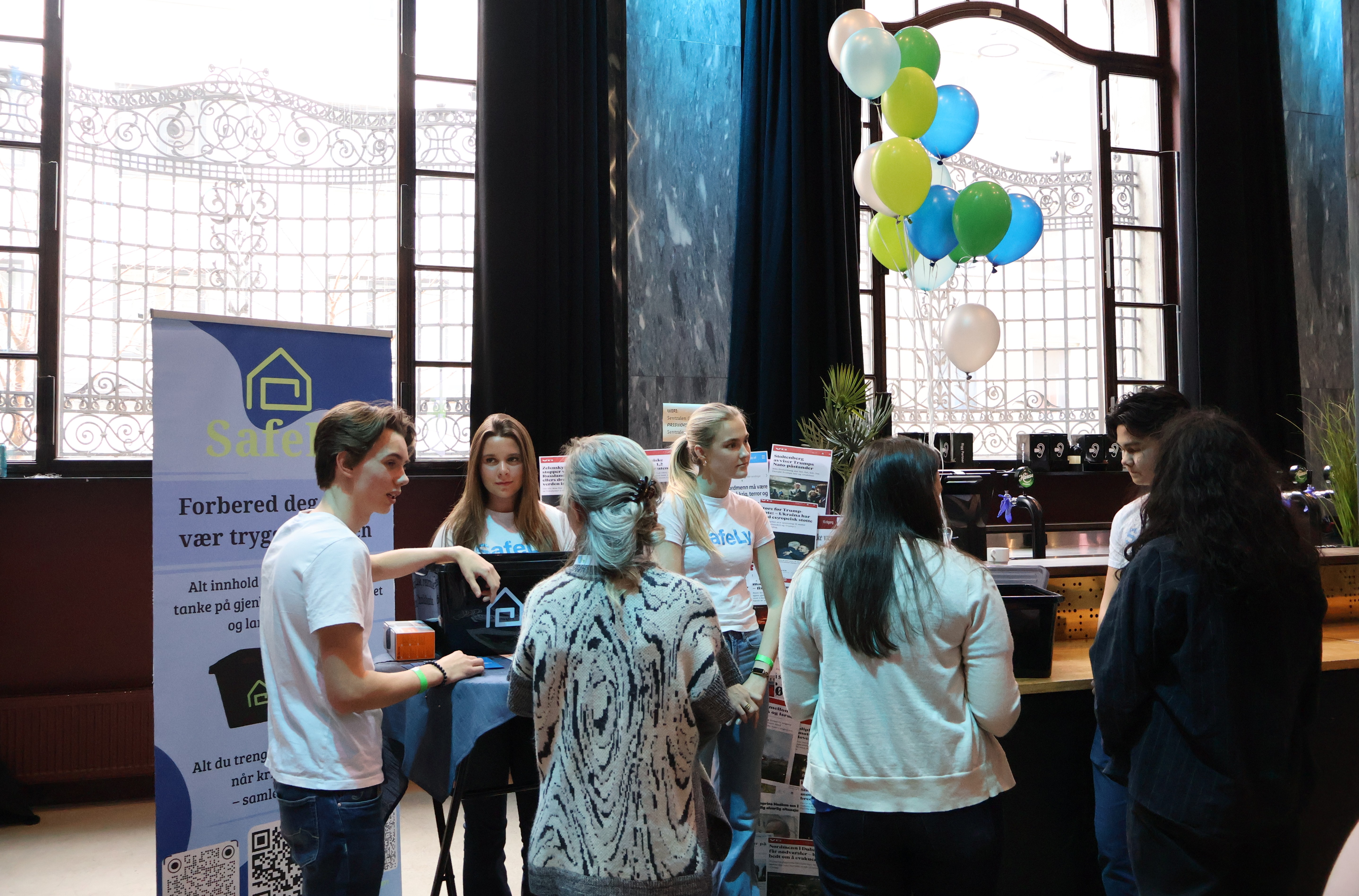 En gruppe mennesker som står foran et skilt med ballonger