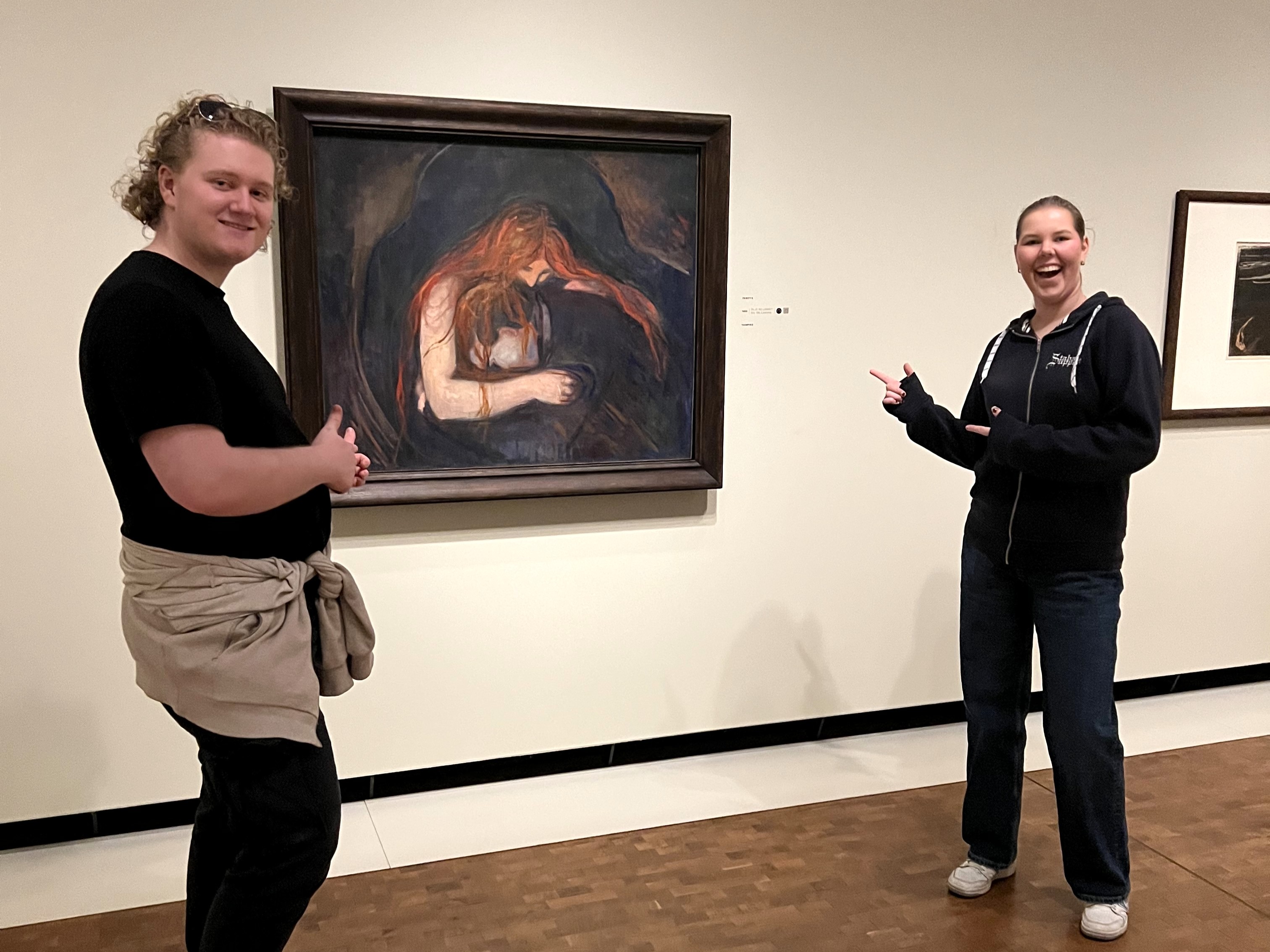 et par personer som poserer for kameraet foran et maleri