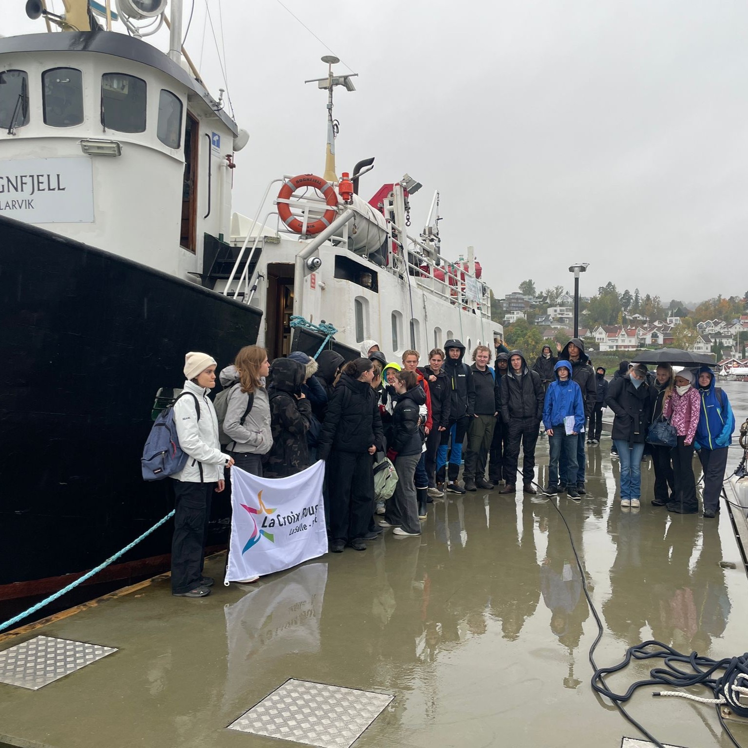 en gruppe mennesker som står på en brygge ved siden av en båt