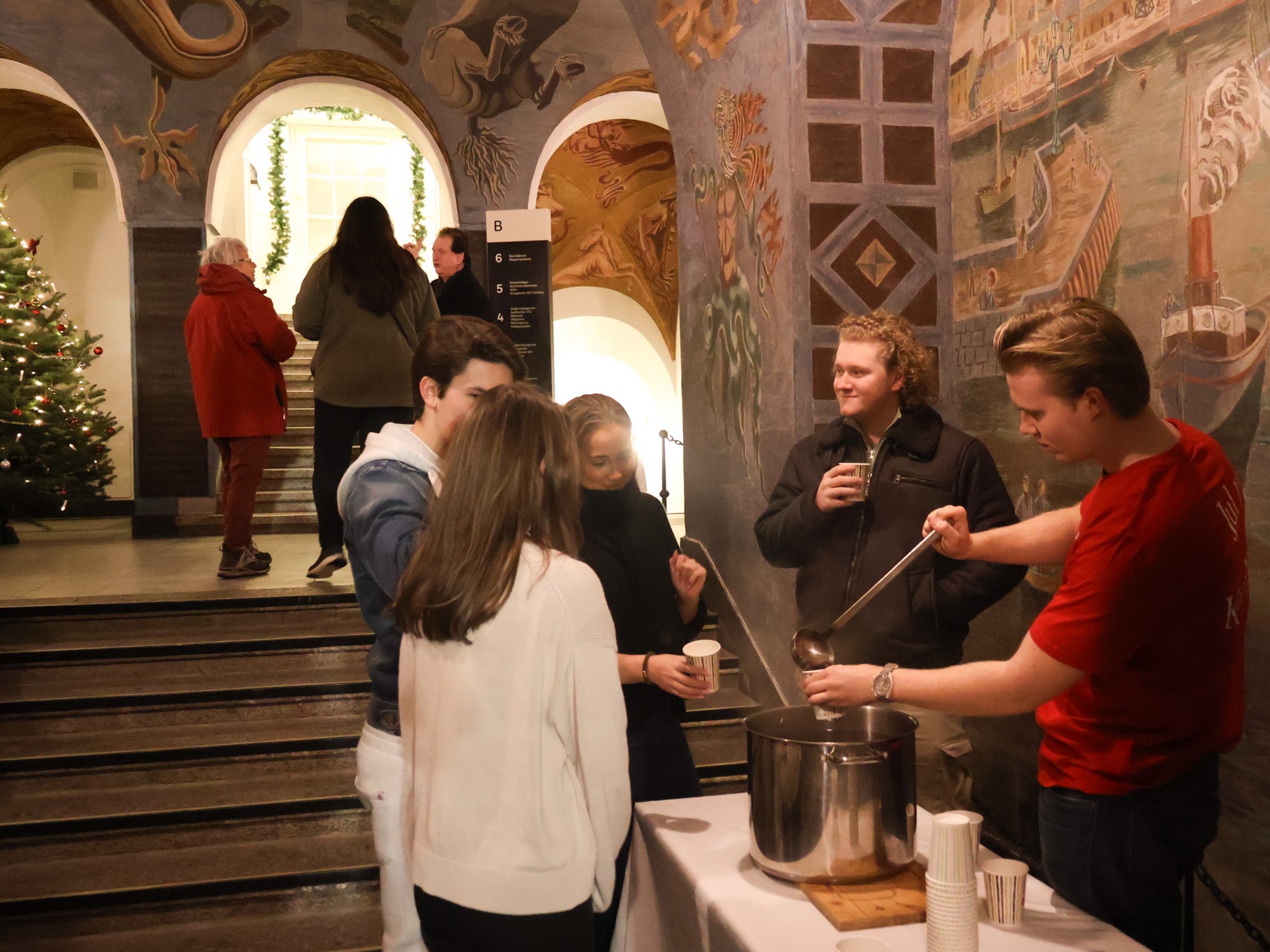 en gruppe mennesker som står rundt et bord med en gryte på