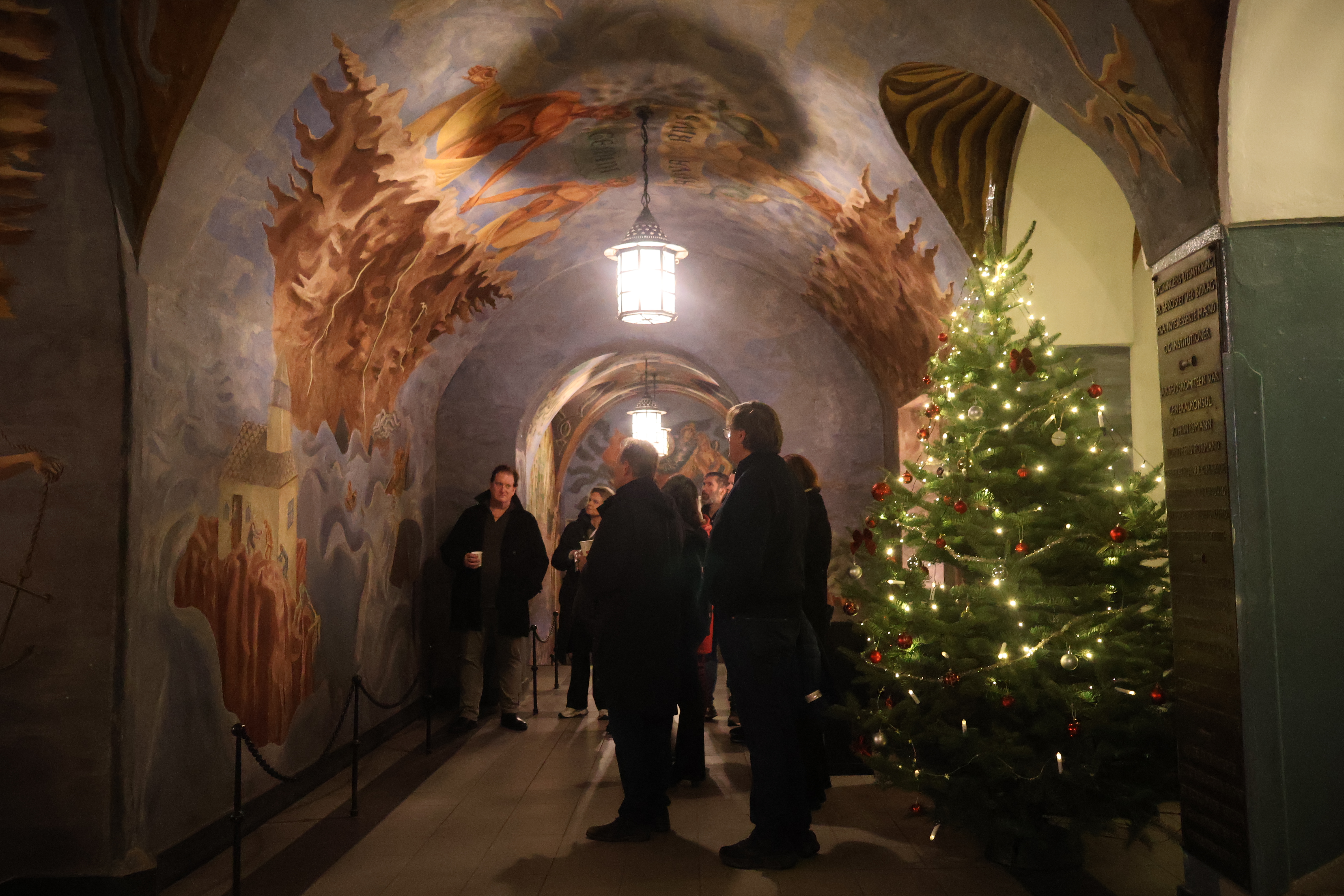En gruppe mennesker som står i en korridor med et juletre