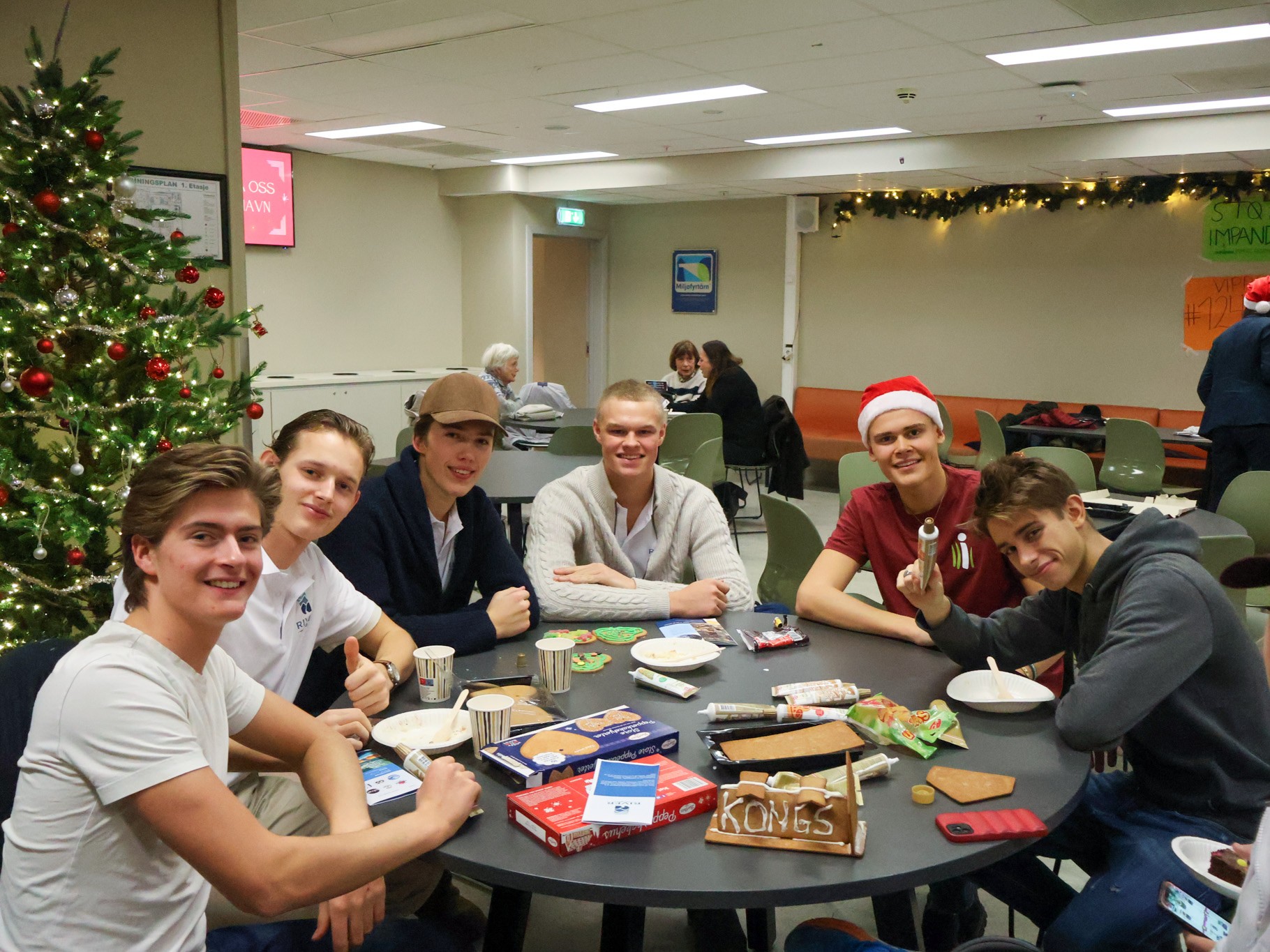 En gruppe mennesker som sitter rundt et bord med mat og drikke